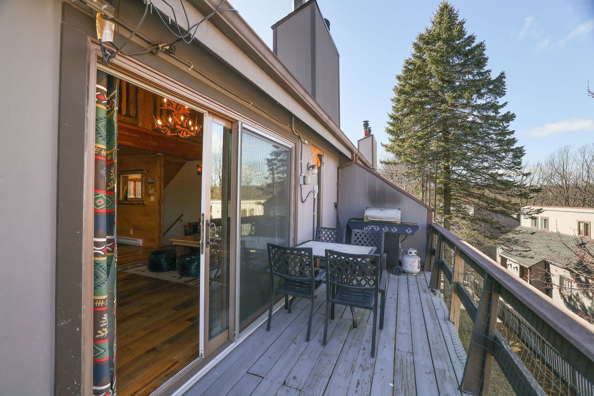 A deck with a table and chairs and a sliding glass door.