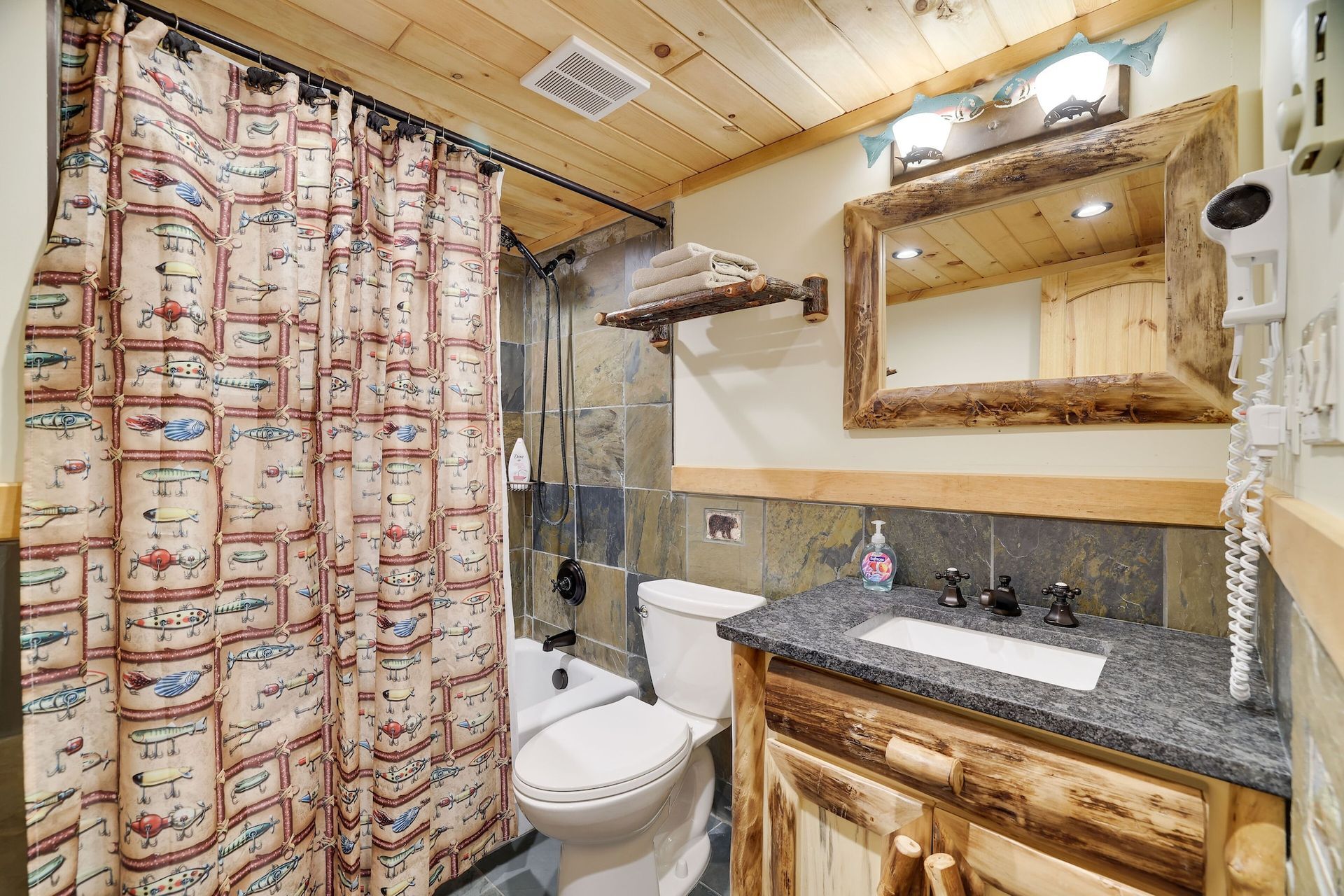 A bathroom with a toilet , sink , mirror and shower curtain.