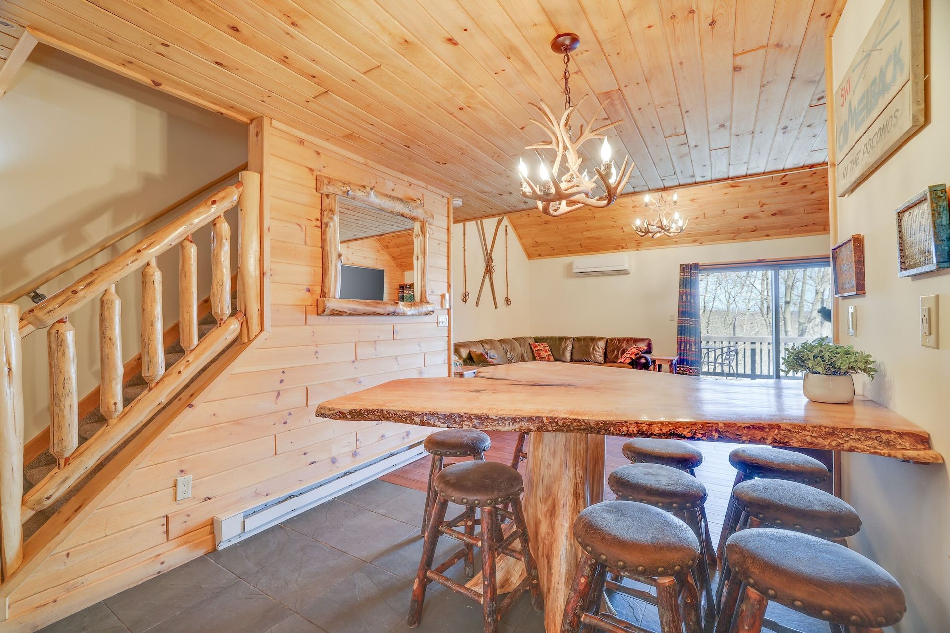 A wooden table with stools in a cabin with a chandelier hanging from the ceiling.