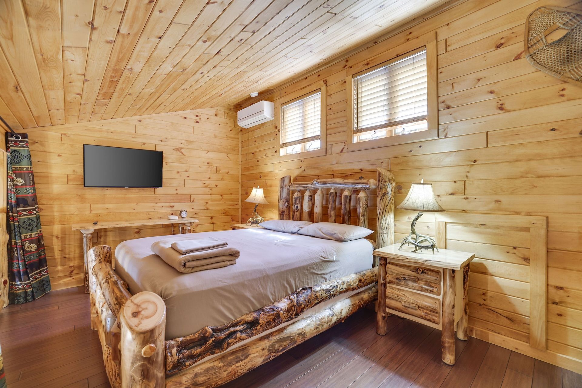 A bedroom in a log cabin with a king size bed and a flat screen tv.