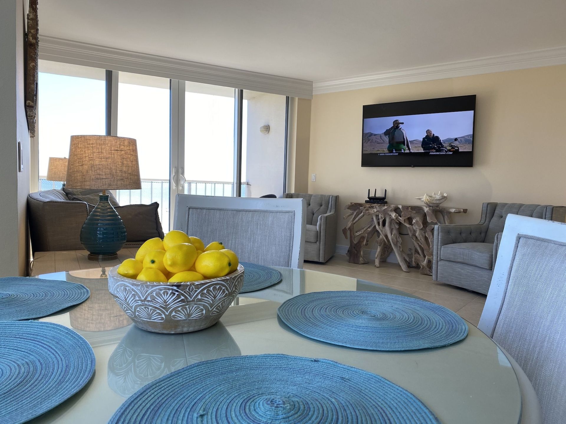 A bowl of lemons sits on a dining table in a living room.