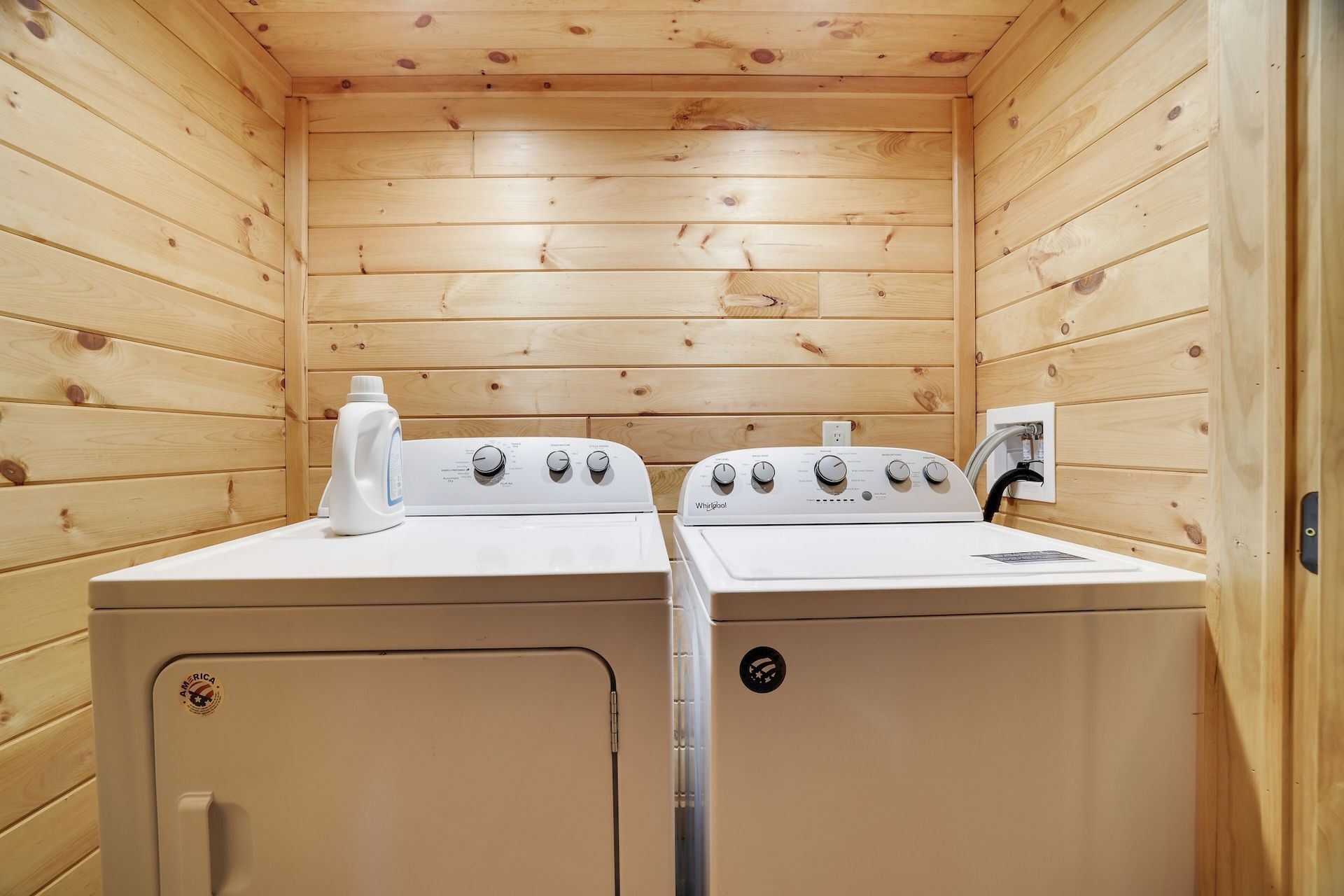 A laundry room with a washer and dryer in a log cabin.