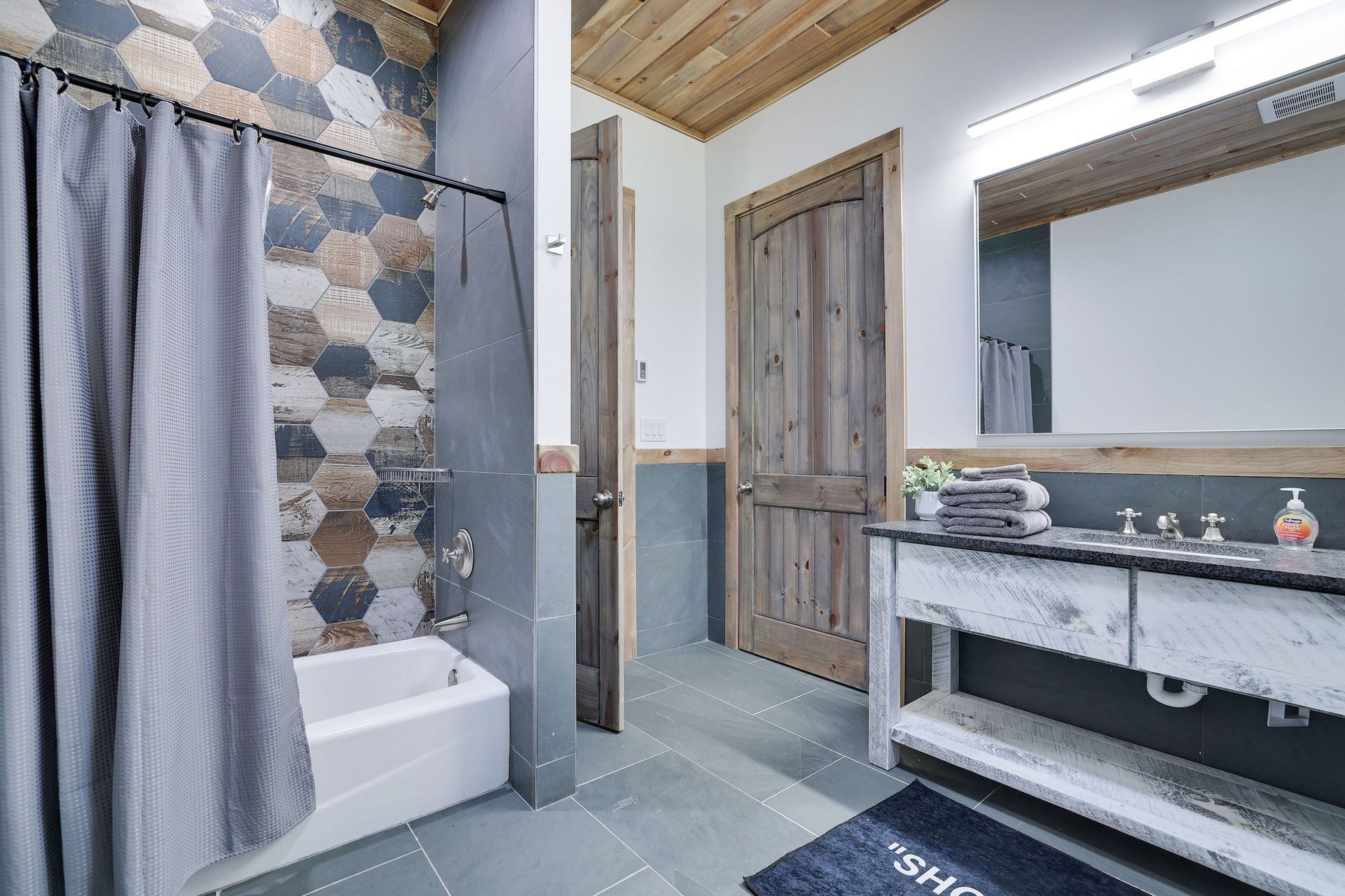 A bathroom with a bathtub , sink , mirror and shower curtain.