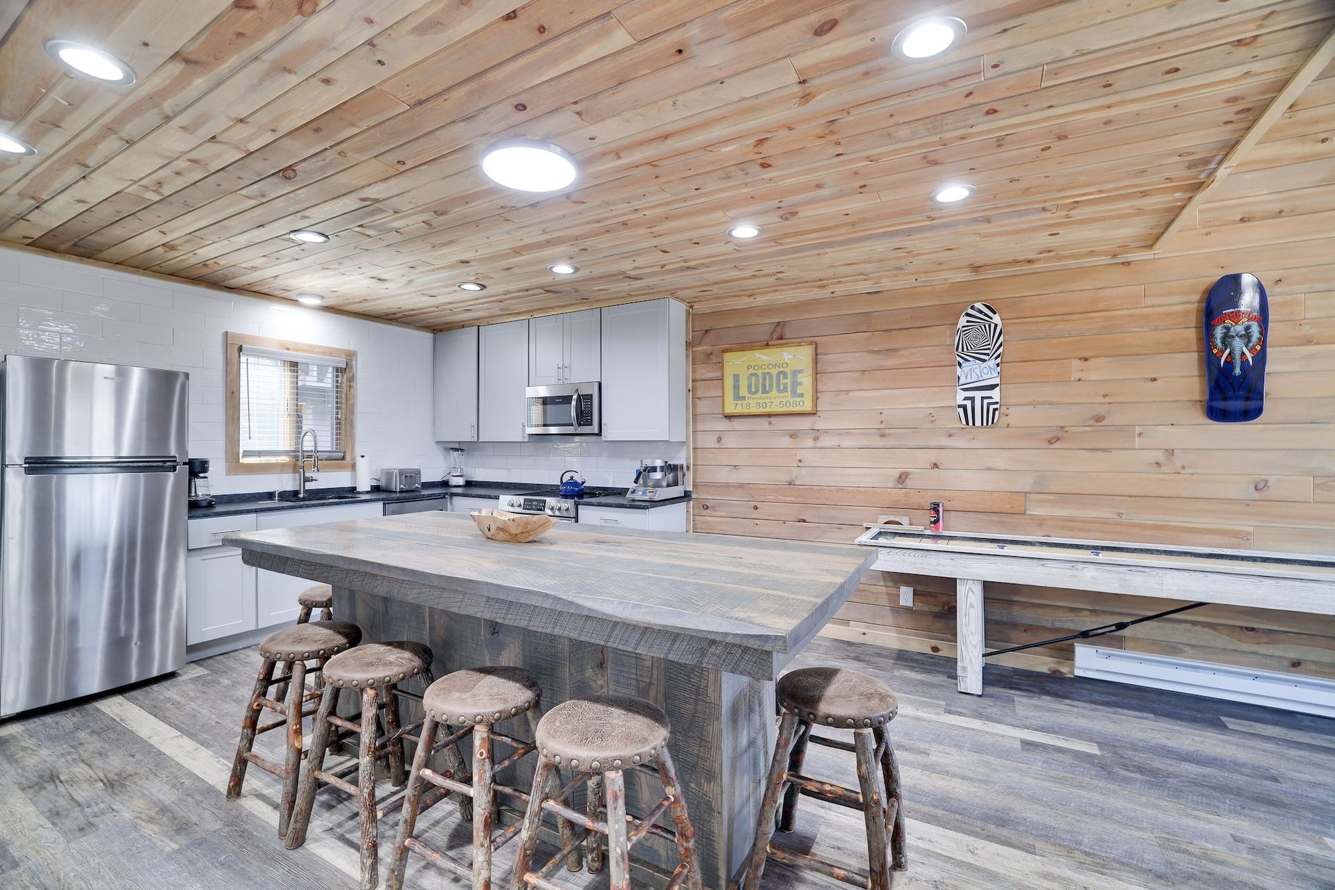 A kitchen with a large island , stools and a refrigerator.