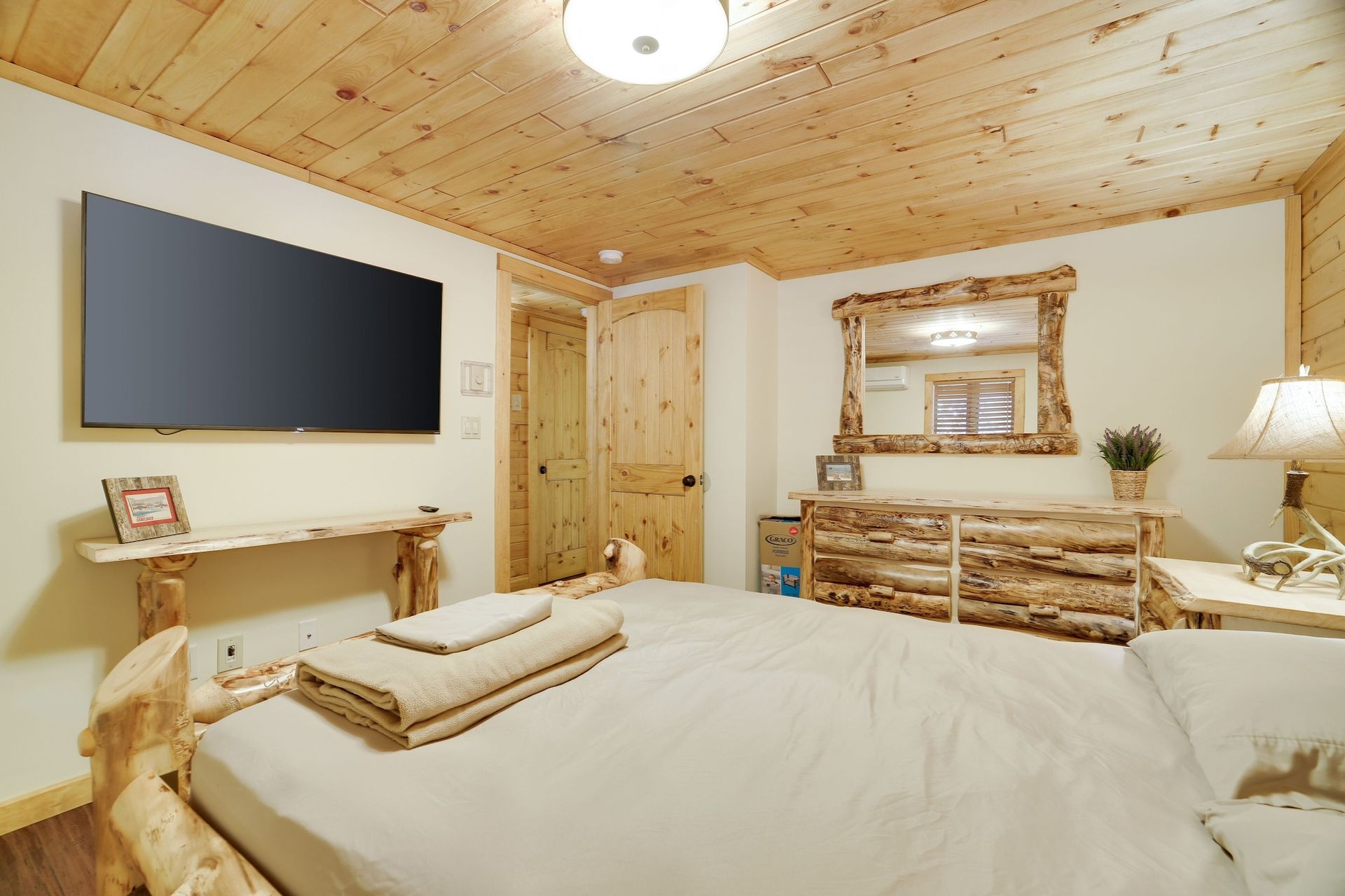 A bedroom with a large bed and a flat screen tv on the wall.