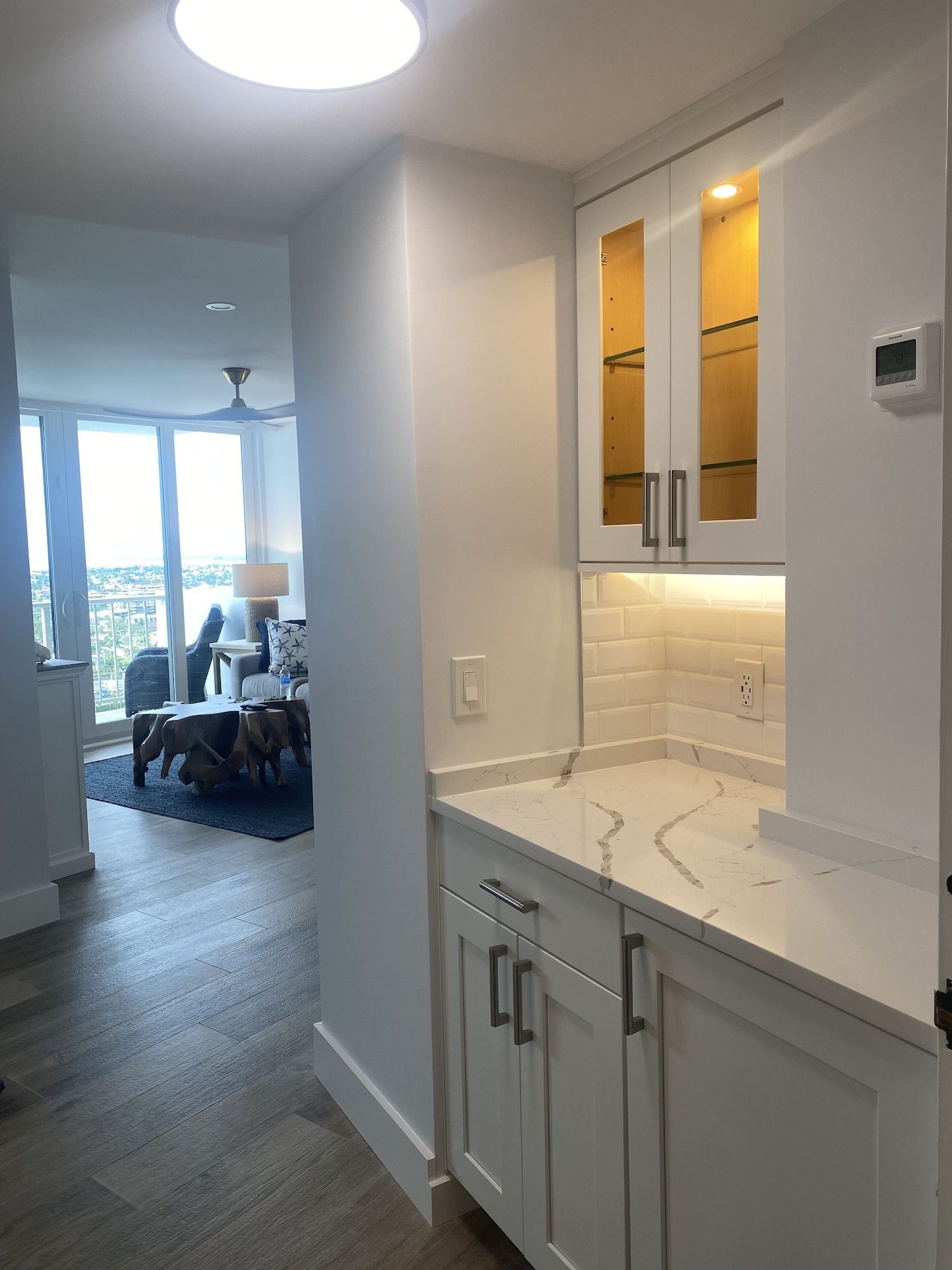 A kitchen with white cabinets and a thermostat on the wall.
