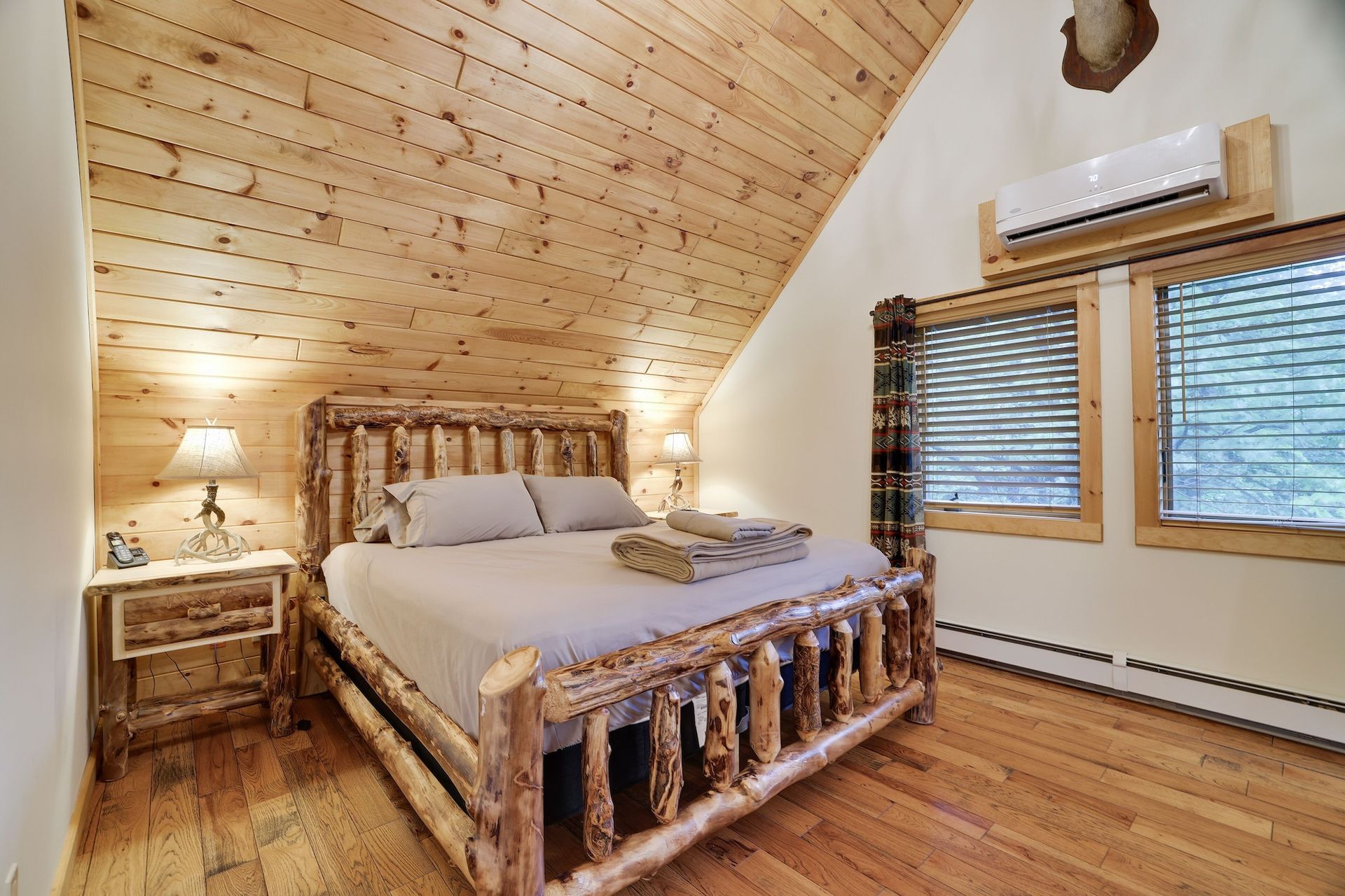 A bedroom with a log bed , two nightstands , and two windows.