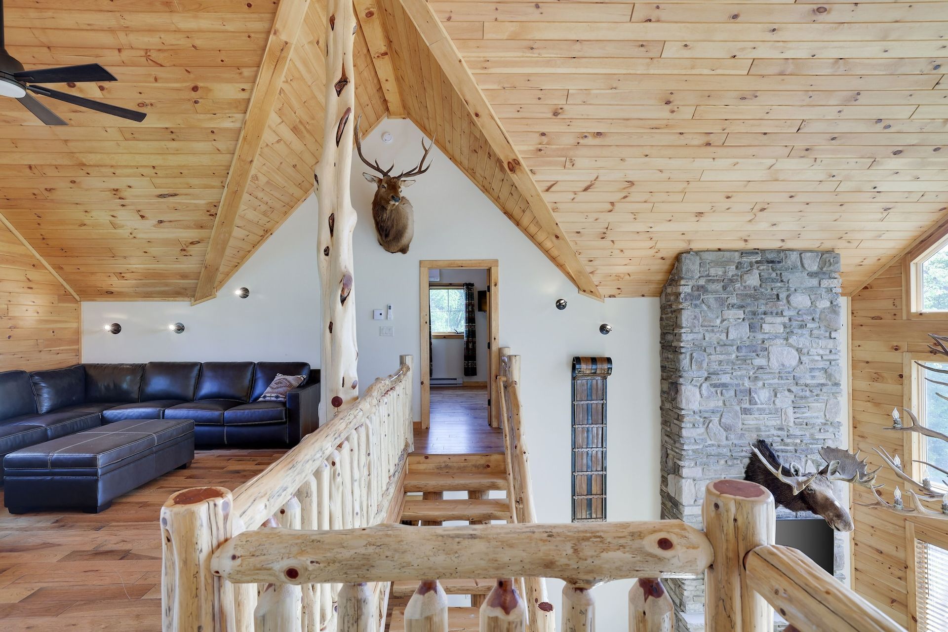 A living room in a log cabin with a deer head on the ceiling.