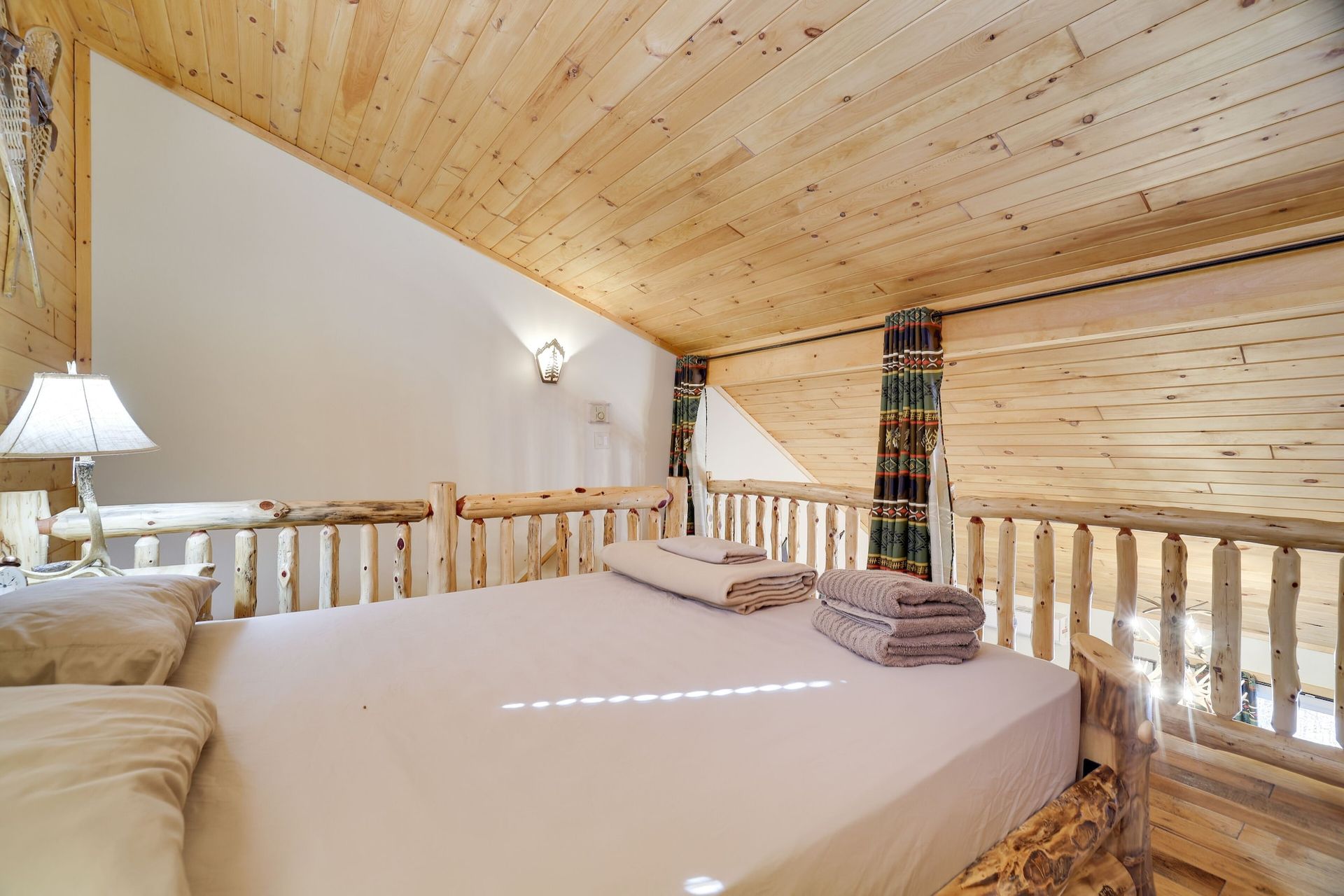 A bedroom in a log cabin with a bed and a lamp.