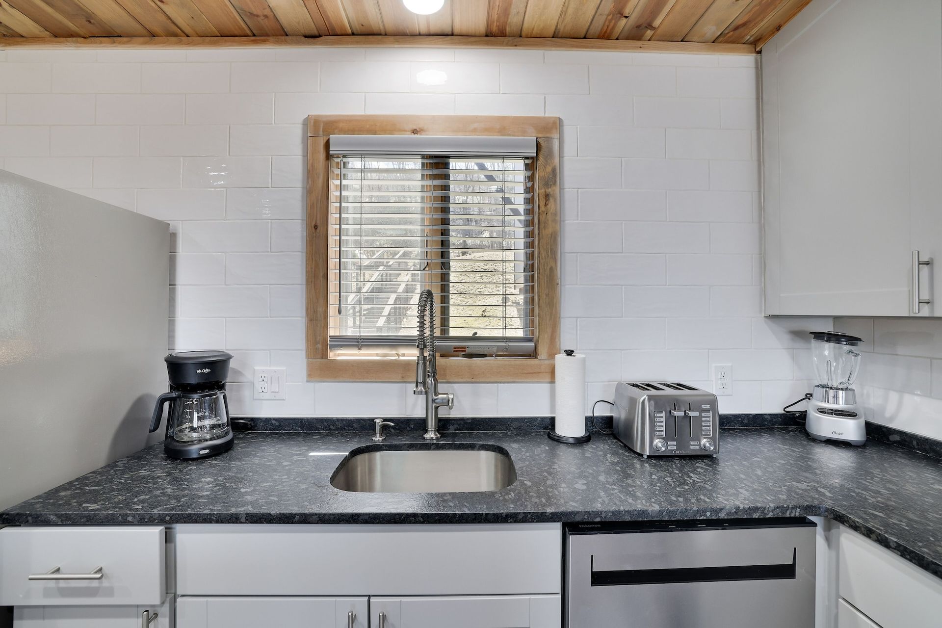 A kitchen with a sink and a window with blinds