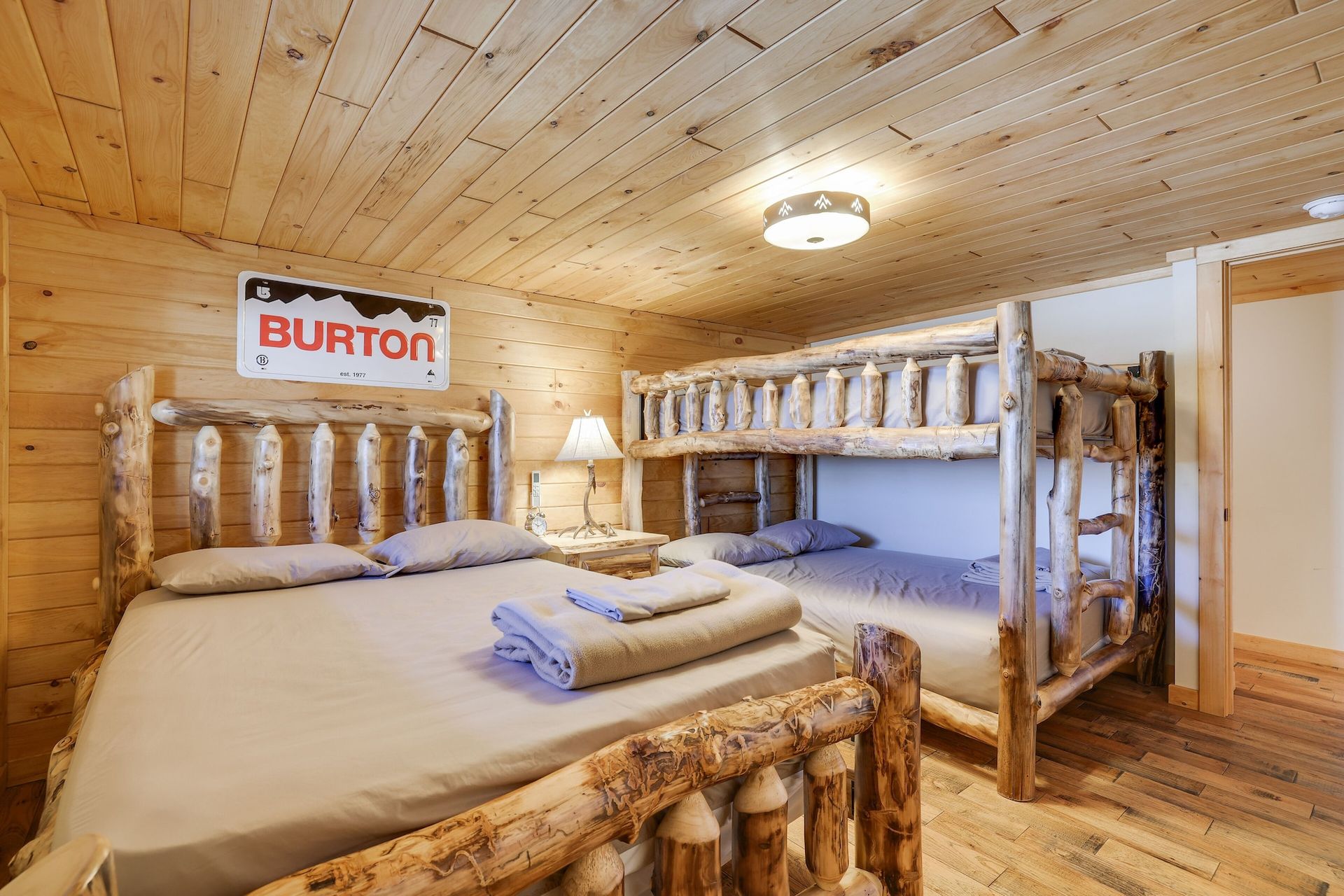 A bedroom with two beds and a bunk bed with a burton sign on the wall.