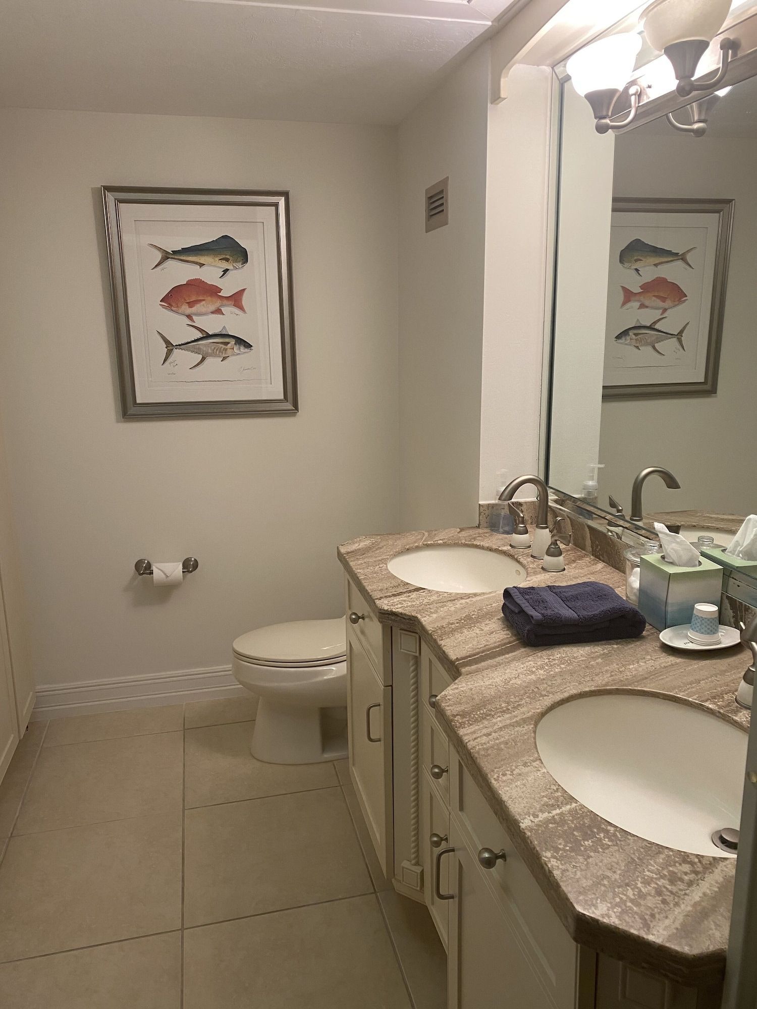 A bathroom with two sinks , a toilet and a mirror.