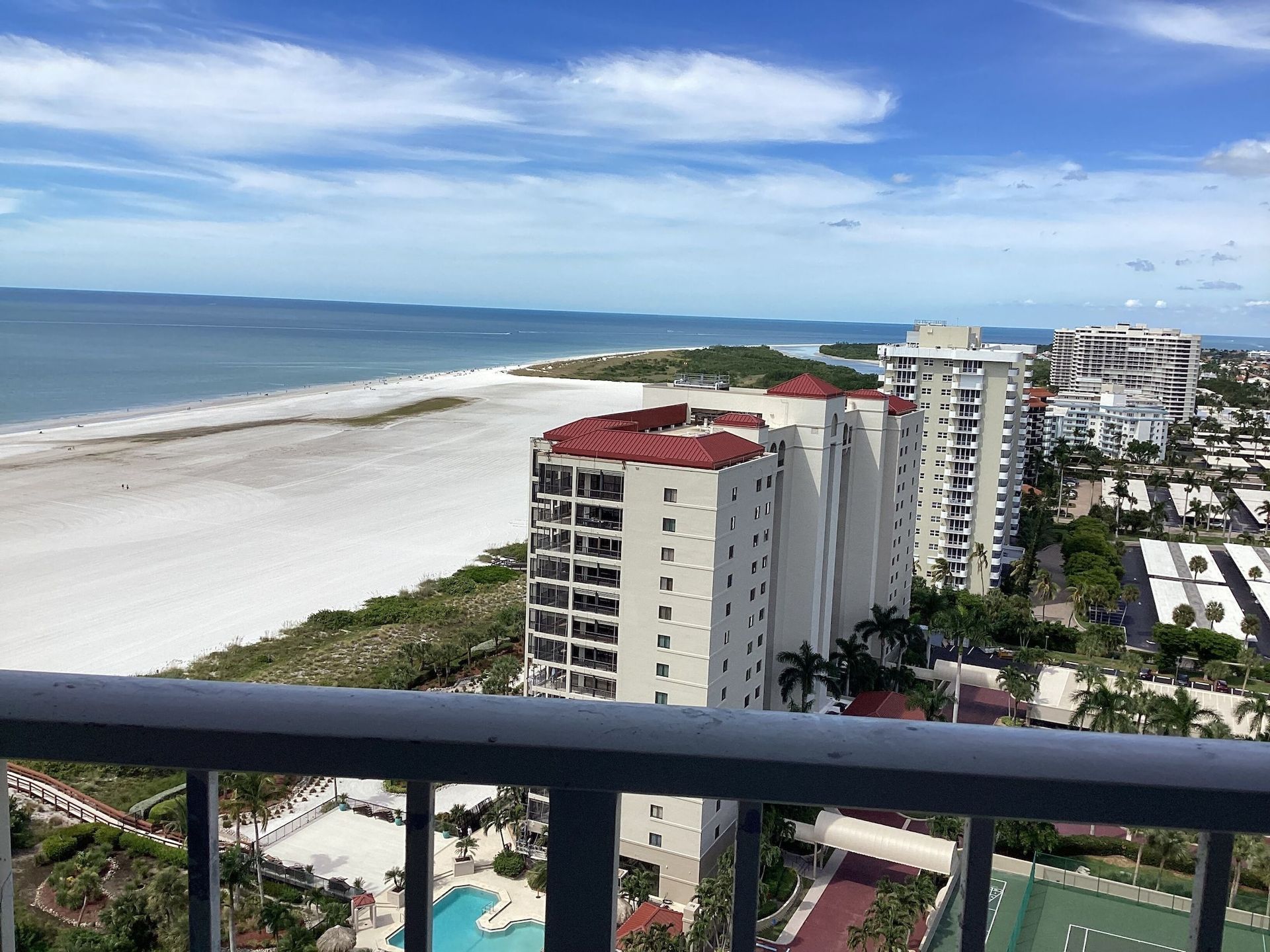 A view of a beach and buildings from a balcony.