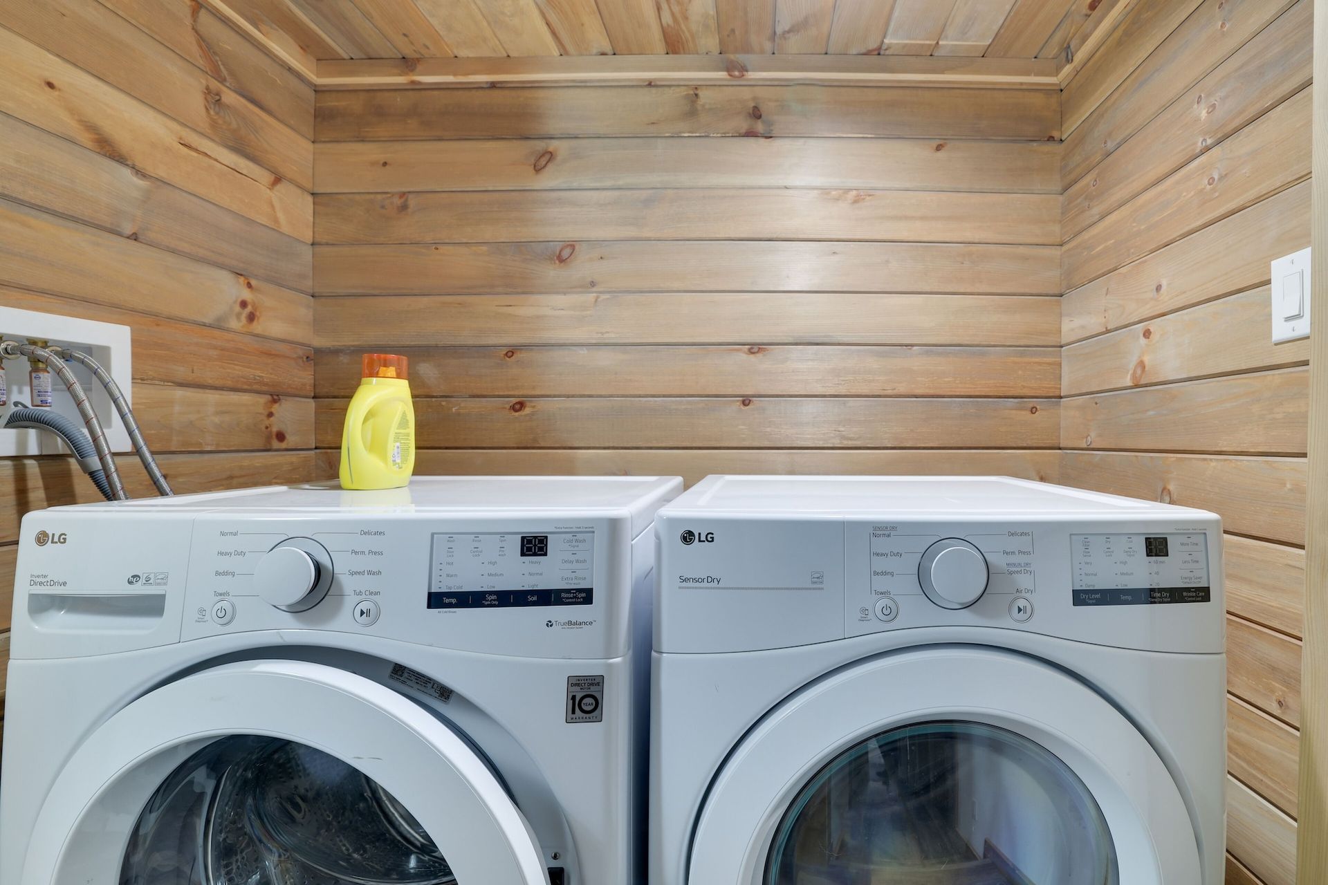 A laundry room with a washer and dryer and a bottle of laundry detergent.