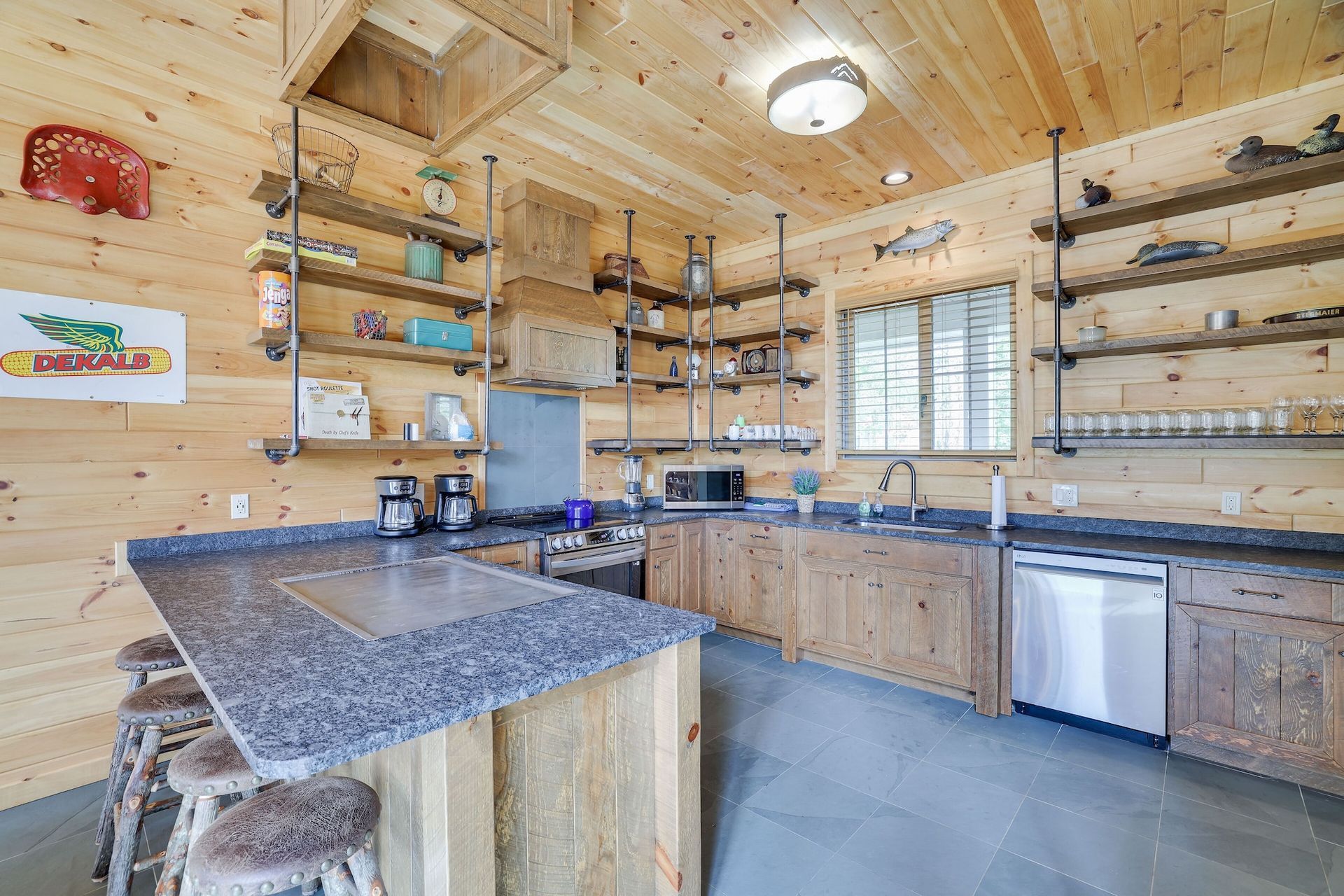 A kitchen in a log cabin with granite counter tops and stainless steel appliances.
