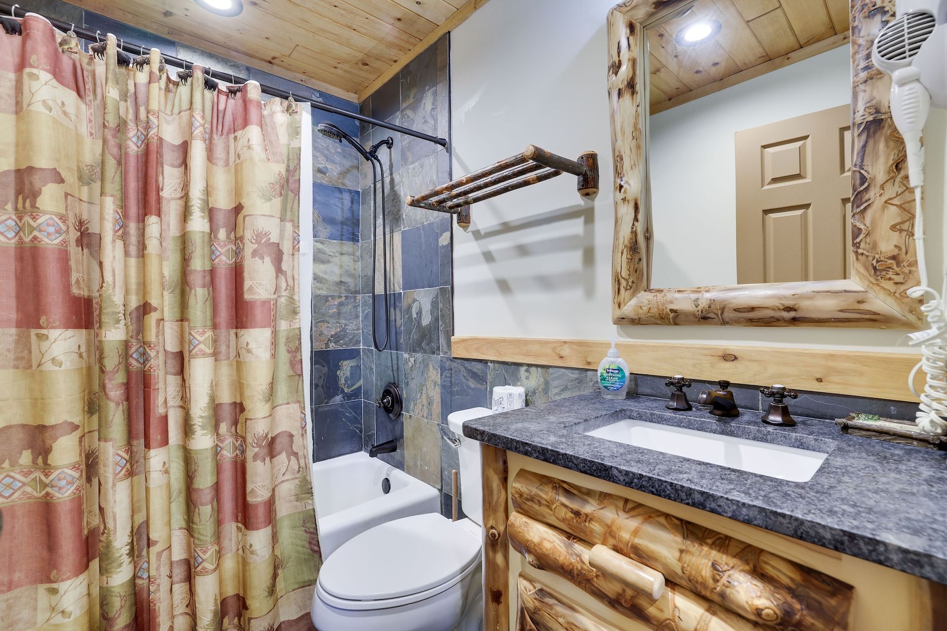 A bathroom with a toilet , sink , mirror and shower curtain.
