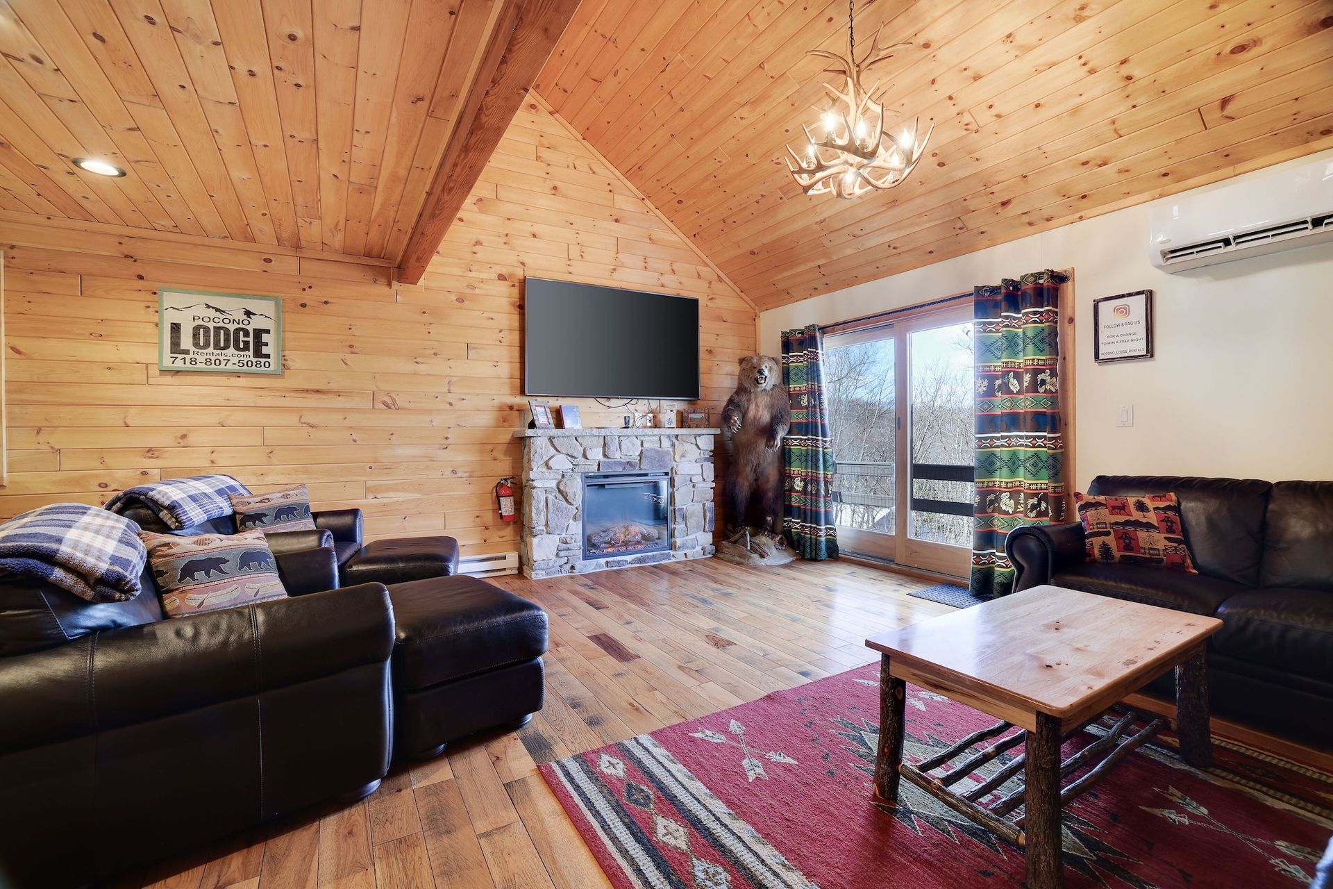 A living room in a log cabin with a fireplace and a flat screen tv.