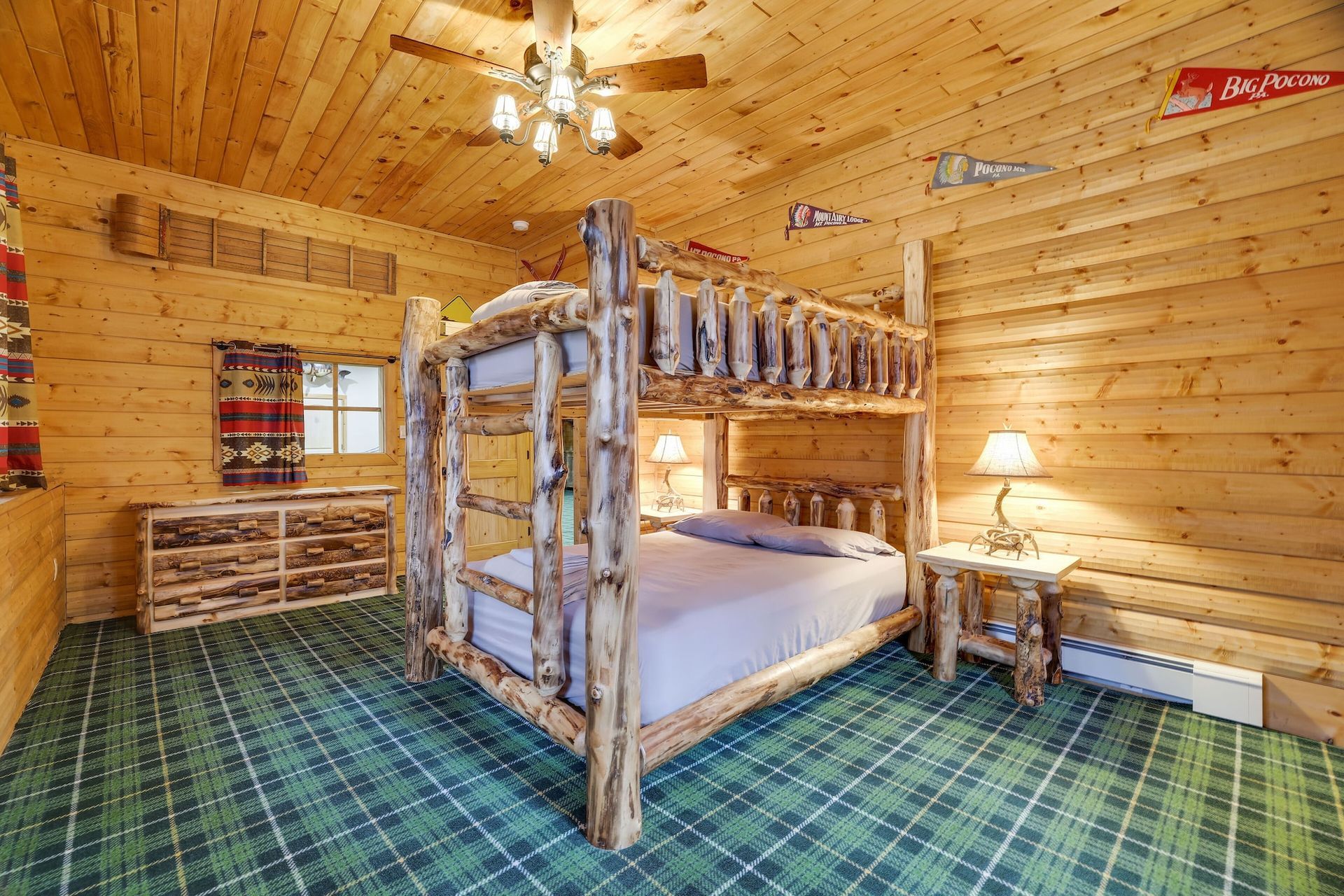 A bedroom in a log cabin with a bunk bed and a ceiling fan.