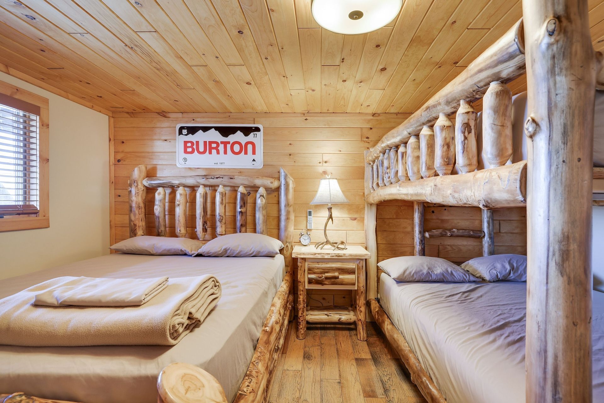 A wooden cabin with three bunk beds and a burton sign on the wall.