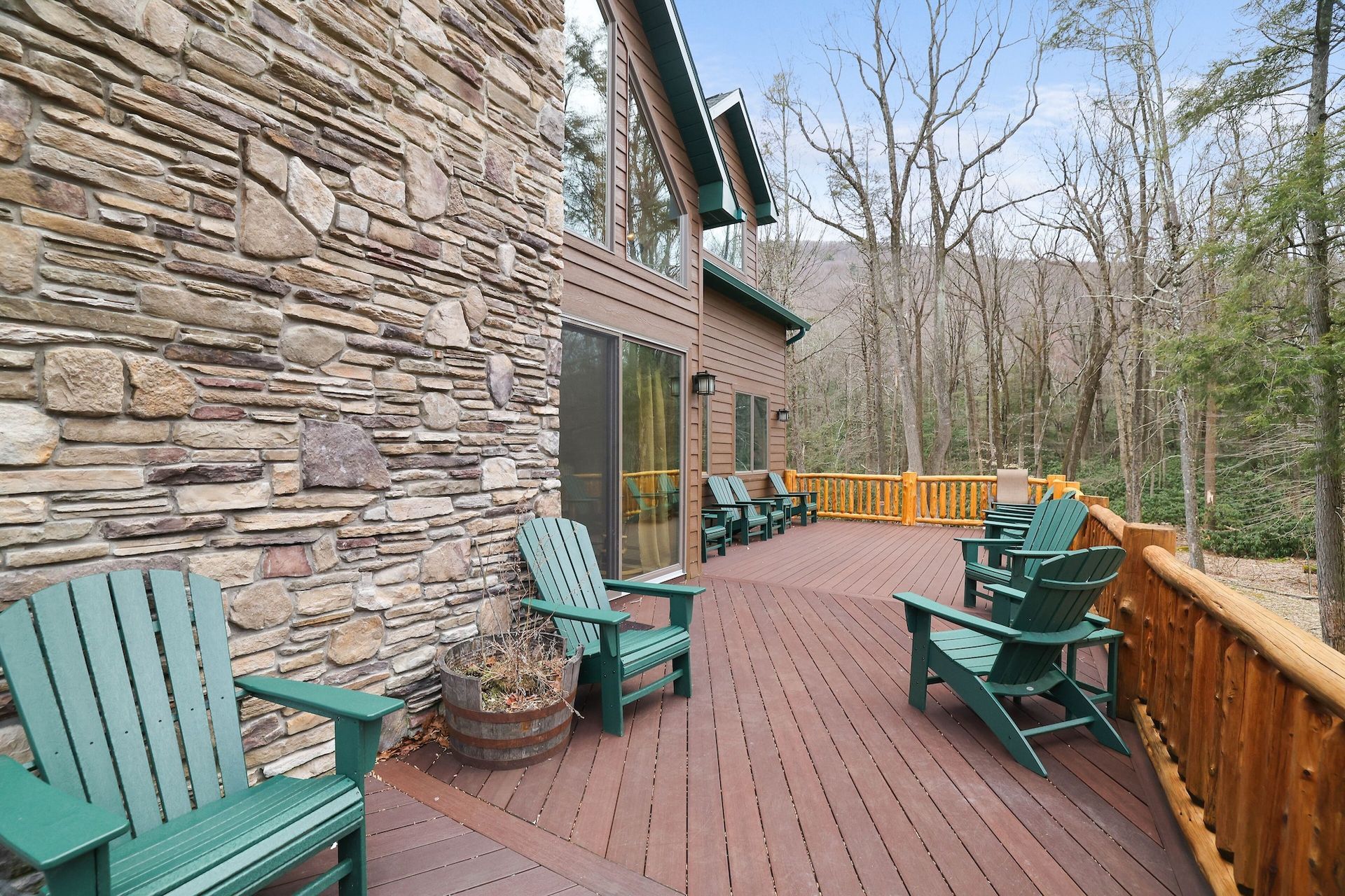 A large deck with green chairs and a stone wall
