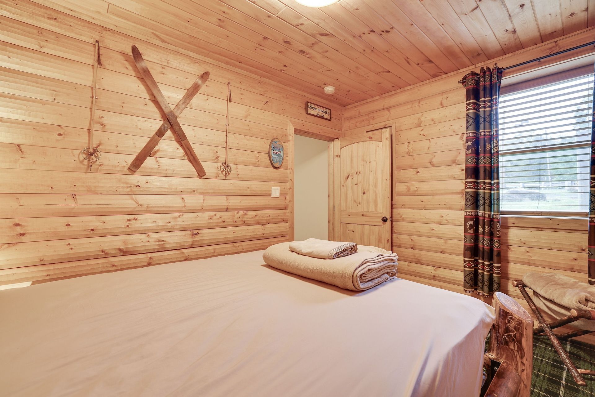 A bedroom in a log cabin with a bed and skis on the wall.