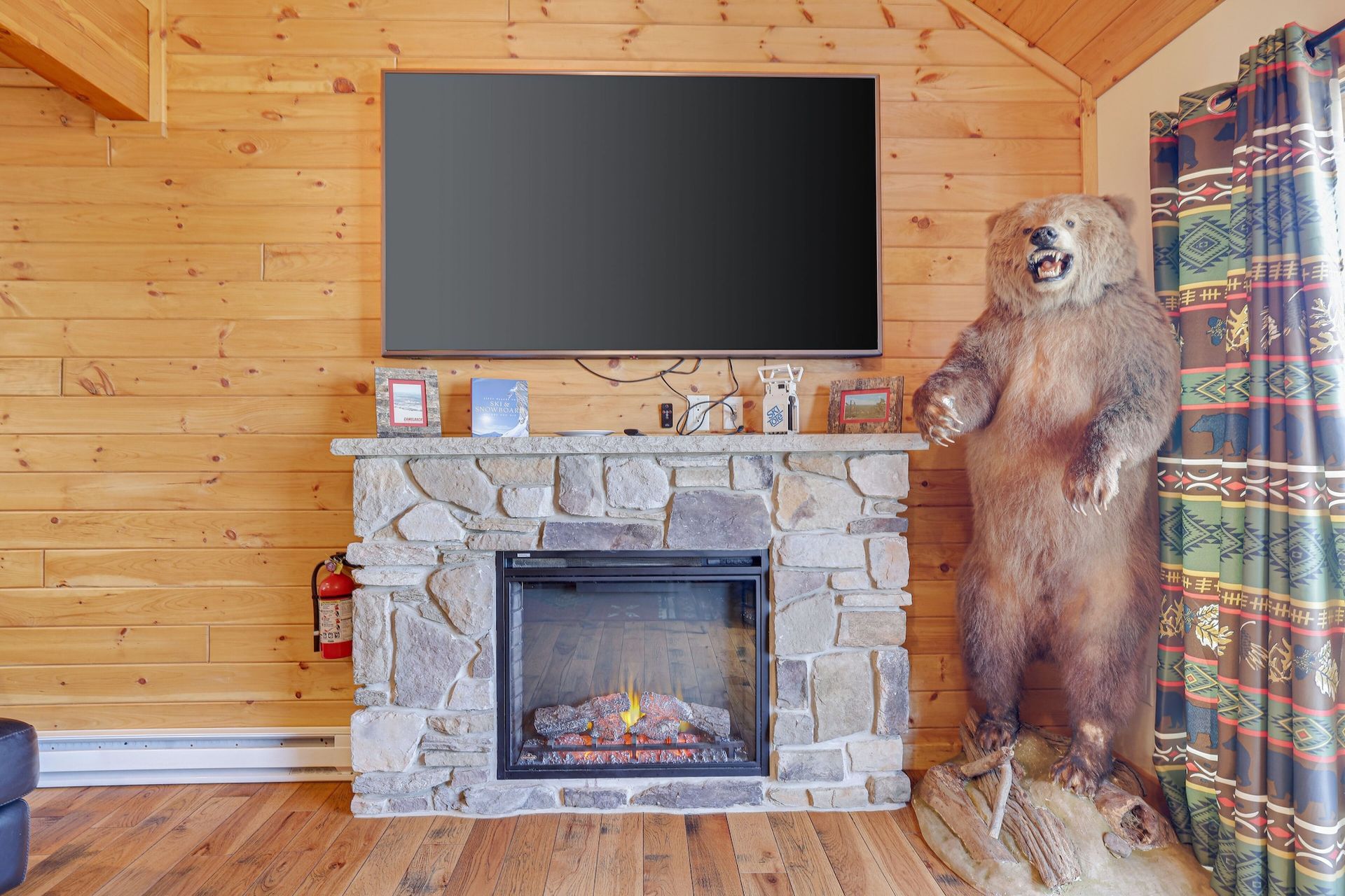 A stuffed bear is standing next to a fireplace in a living room.