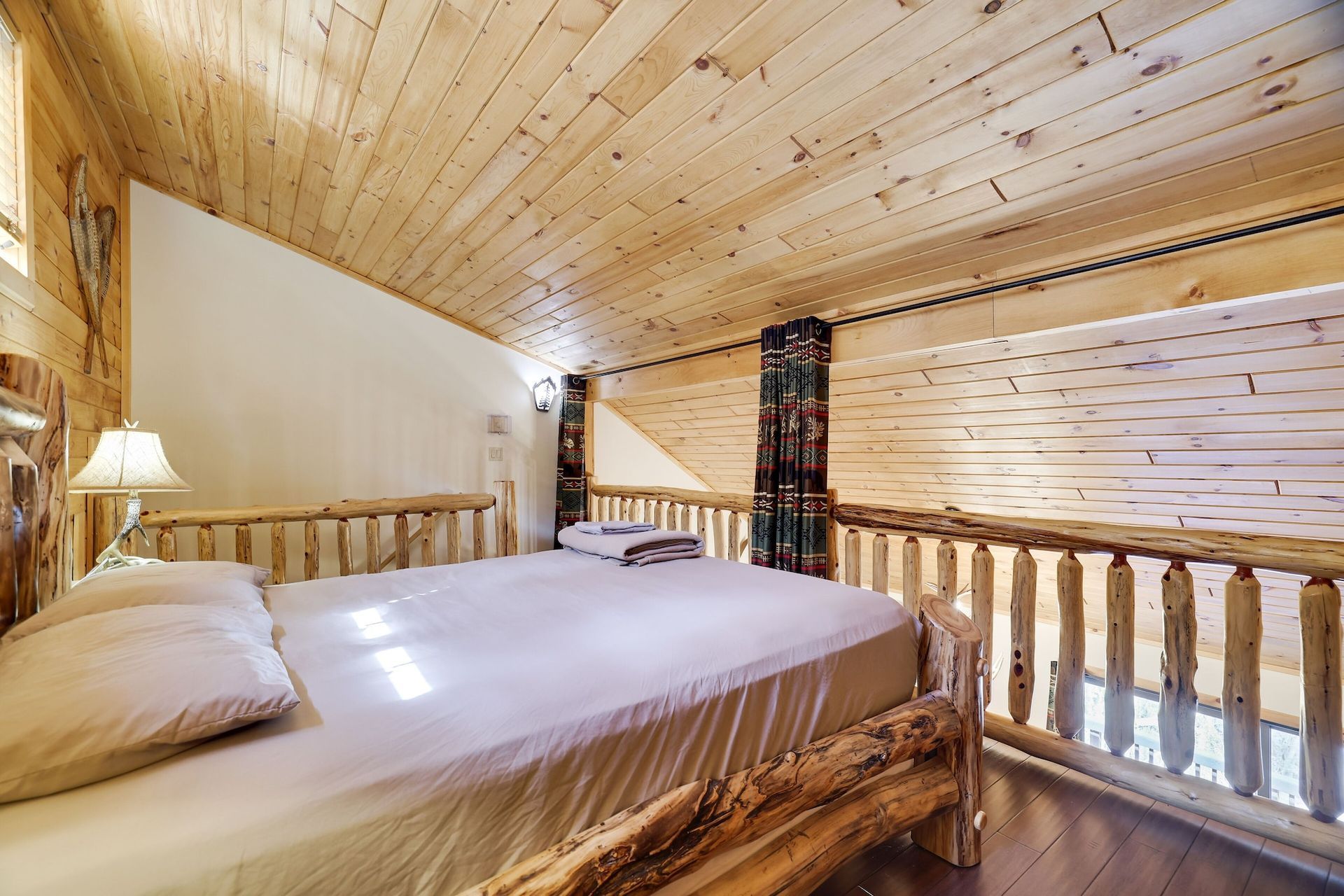 A bedroom in a log cabin with a bed and a balcony.