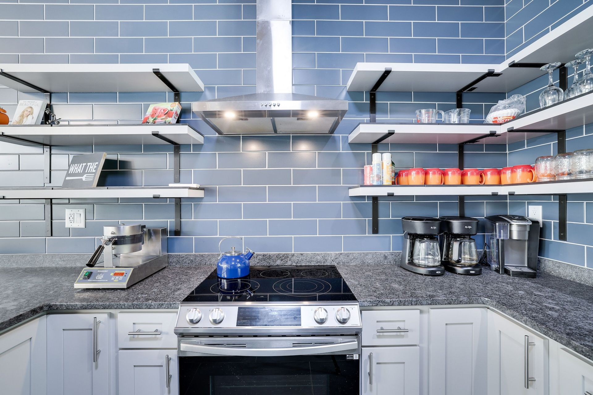 A kitchen with a stove , oven , and shelves.