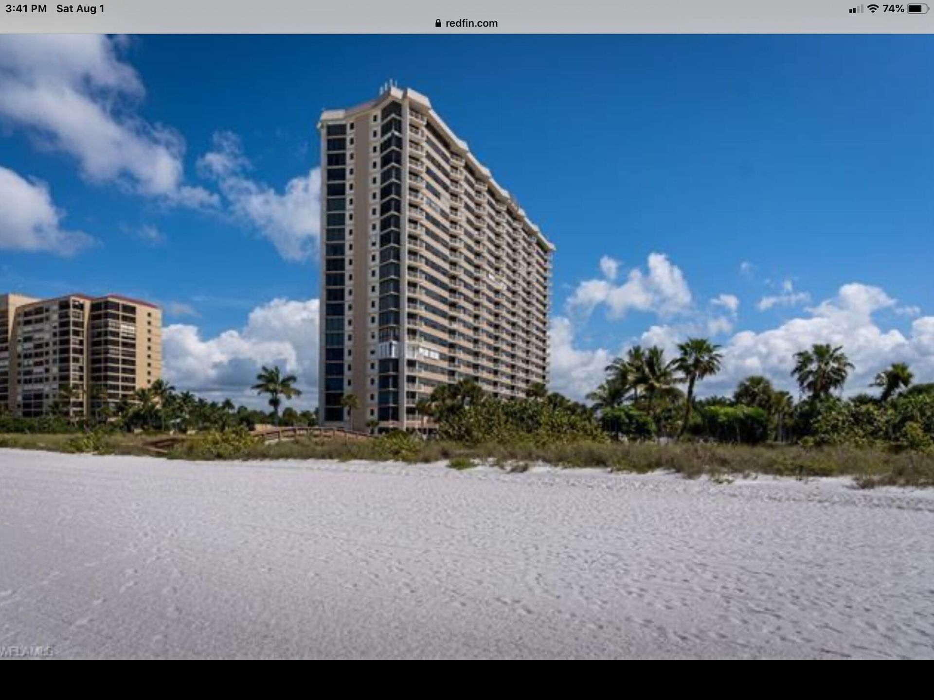 A large building is sitting on top of a sandy beach
