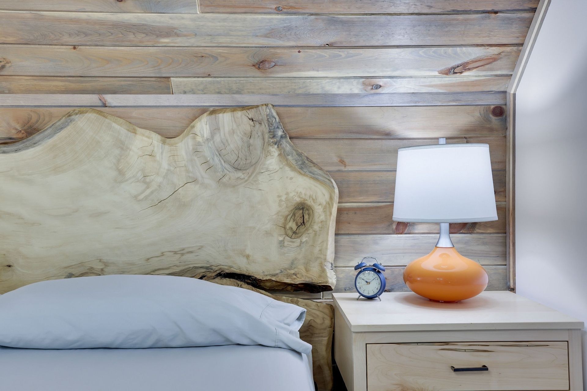 A bed with a wooden headboard and a lamp on a nightstand