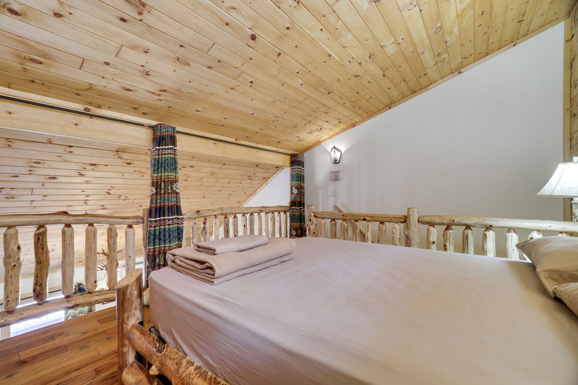 There is a bed in the attic of a cabin.