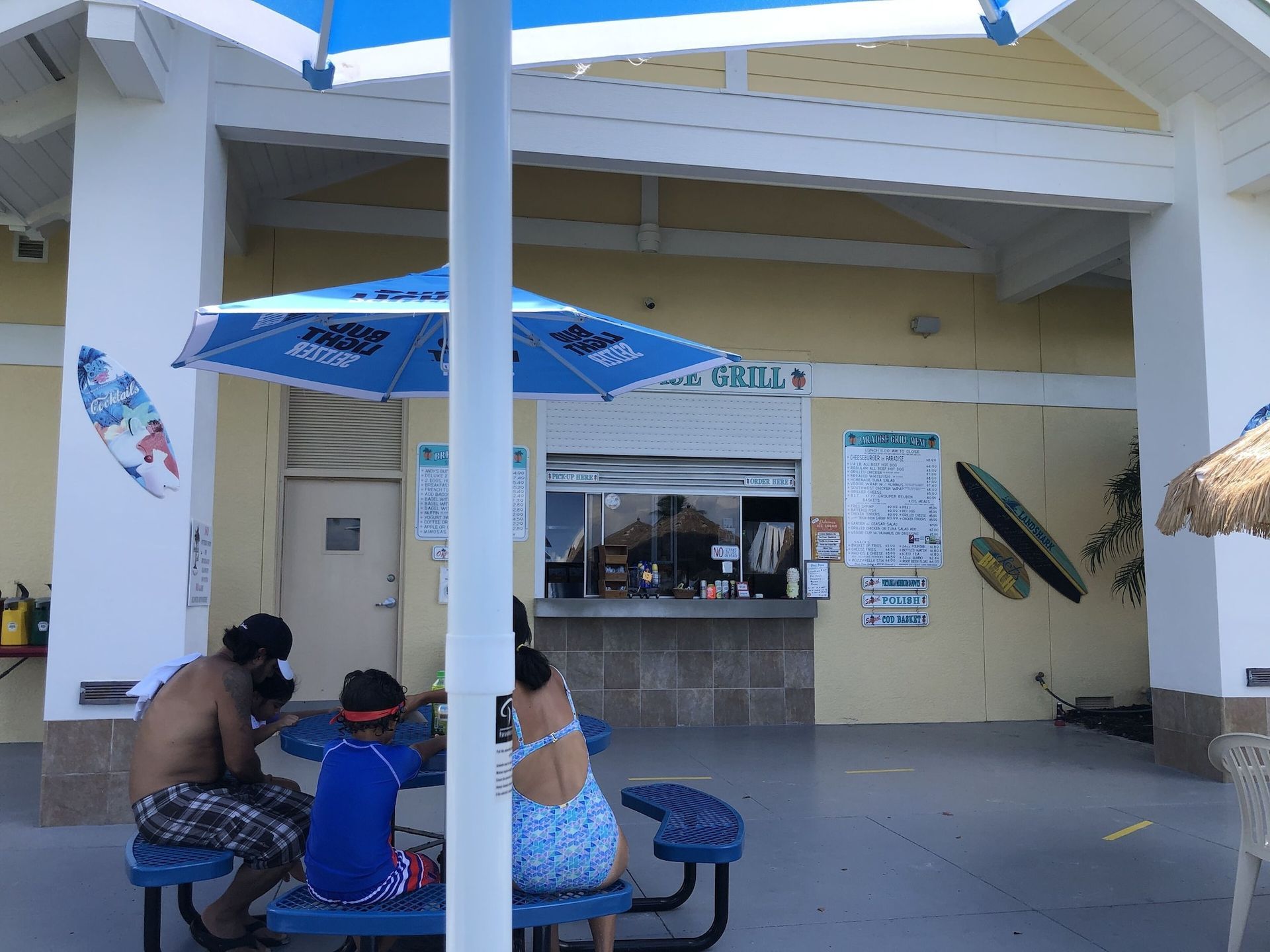 People sitting at picnic tables in front of a grill