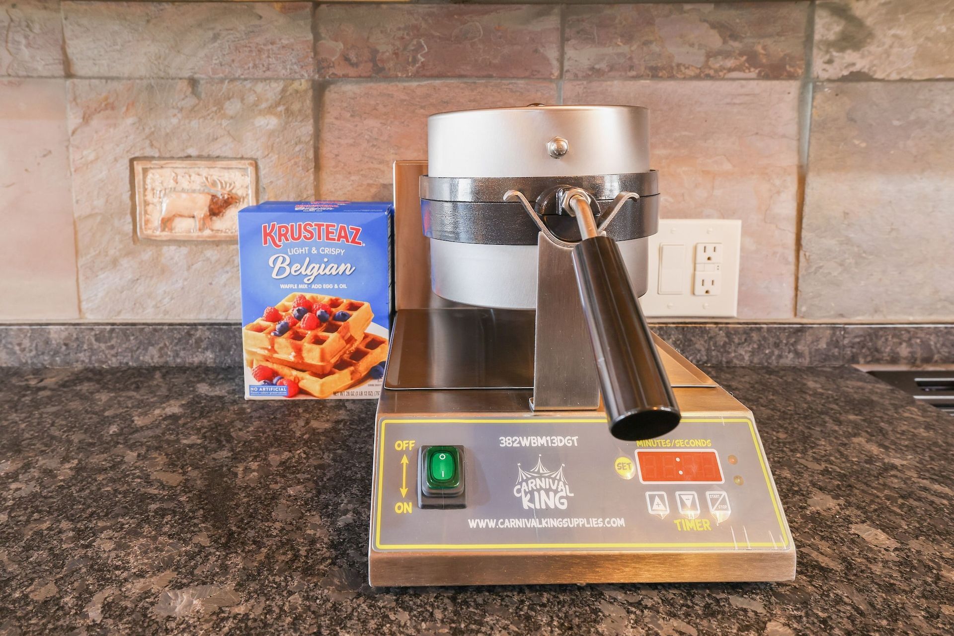 A waffle maker is sitting on a counter next to a box of belgian waffles.