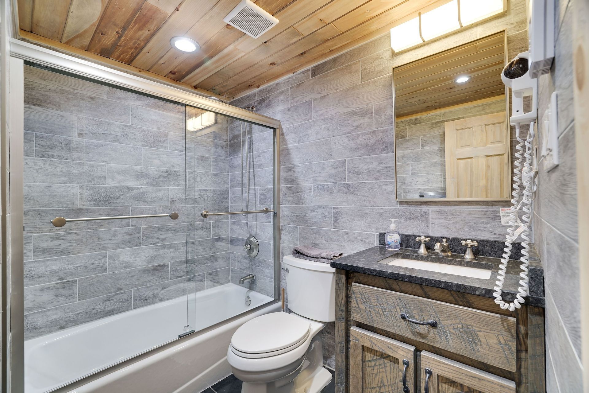 A bathroom with a toilet , sink , bathtub and shower.