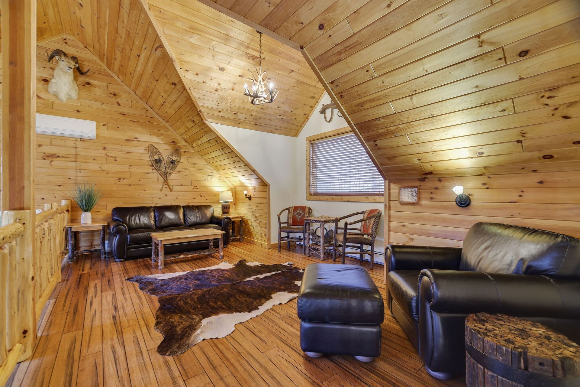 A living room with a couch , chairs , ottoman and a cowhide rug.