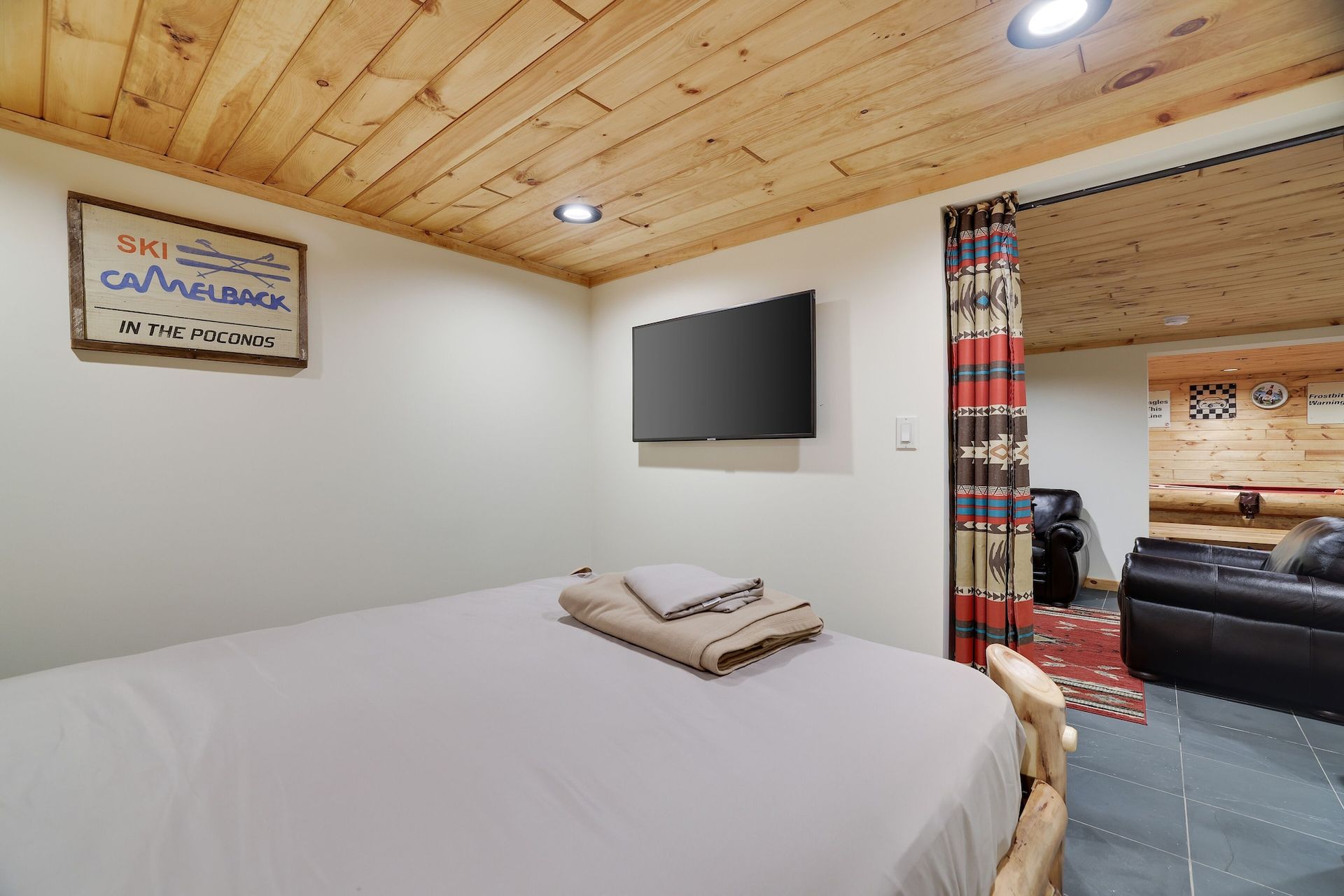 A bedroom with a bed and a flat screen tv on the wall.