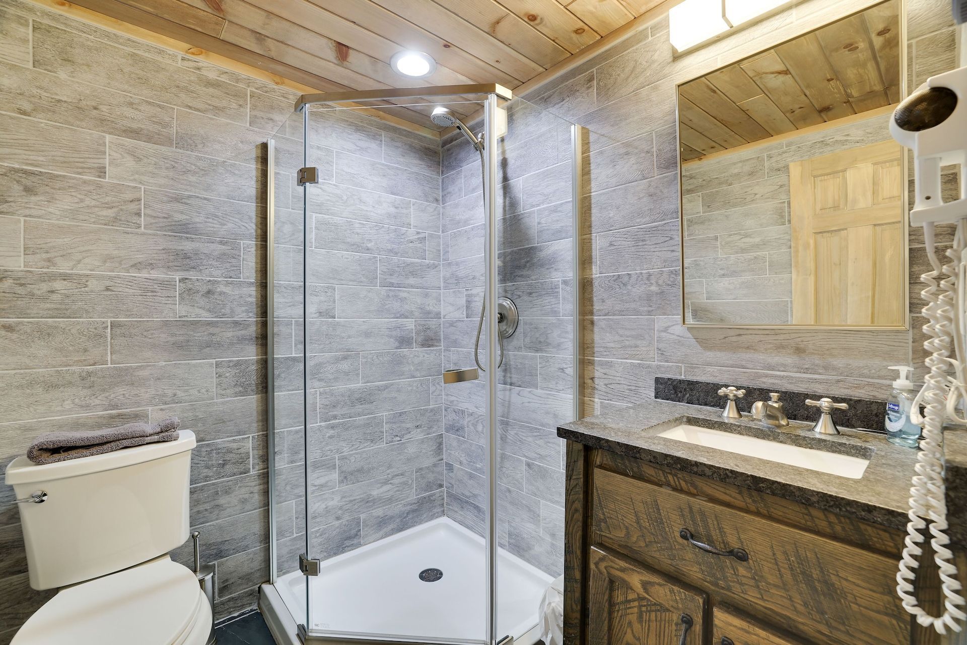 A bathroom with a toilet , sink , shower and mirror.