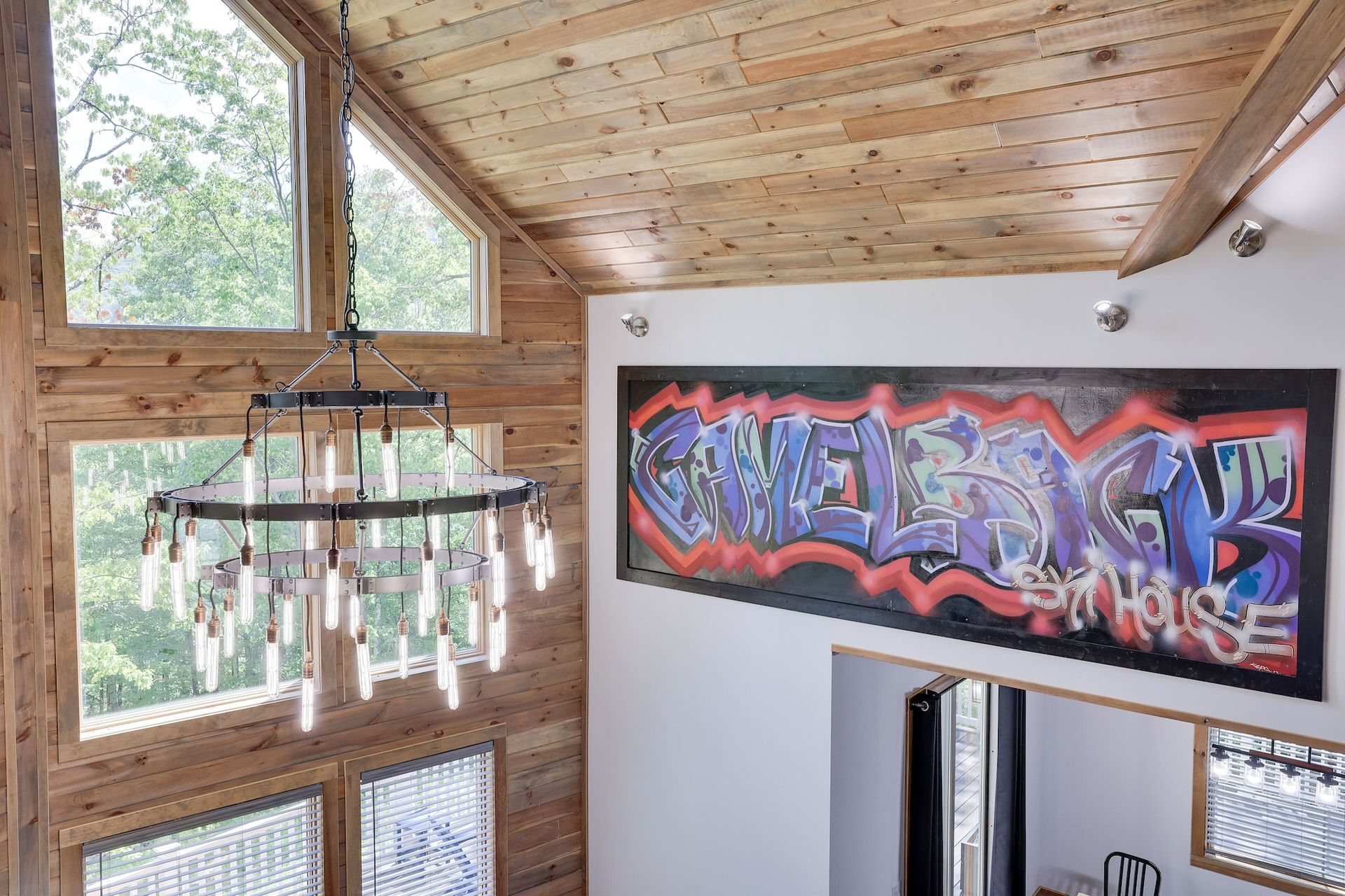 A room with a large painting on the wall and a chandelier hanging from the ceiling.