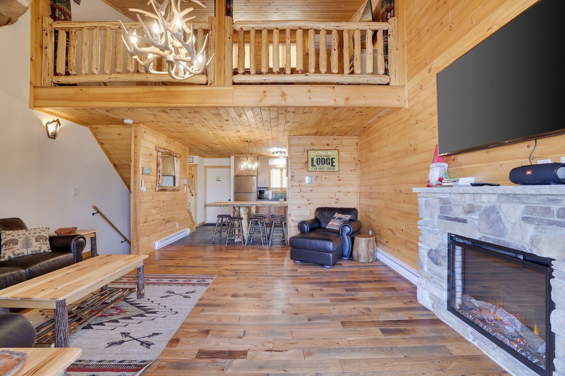A living room in a log cabin with a fireplace and a flat screen tv.
