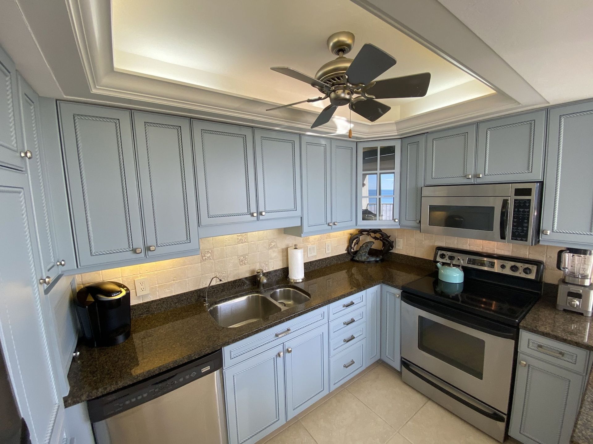 A kitchen with stainless steel appliances and a ceiling fan.