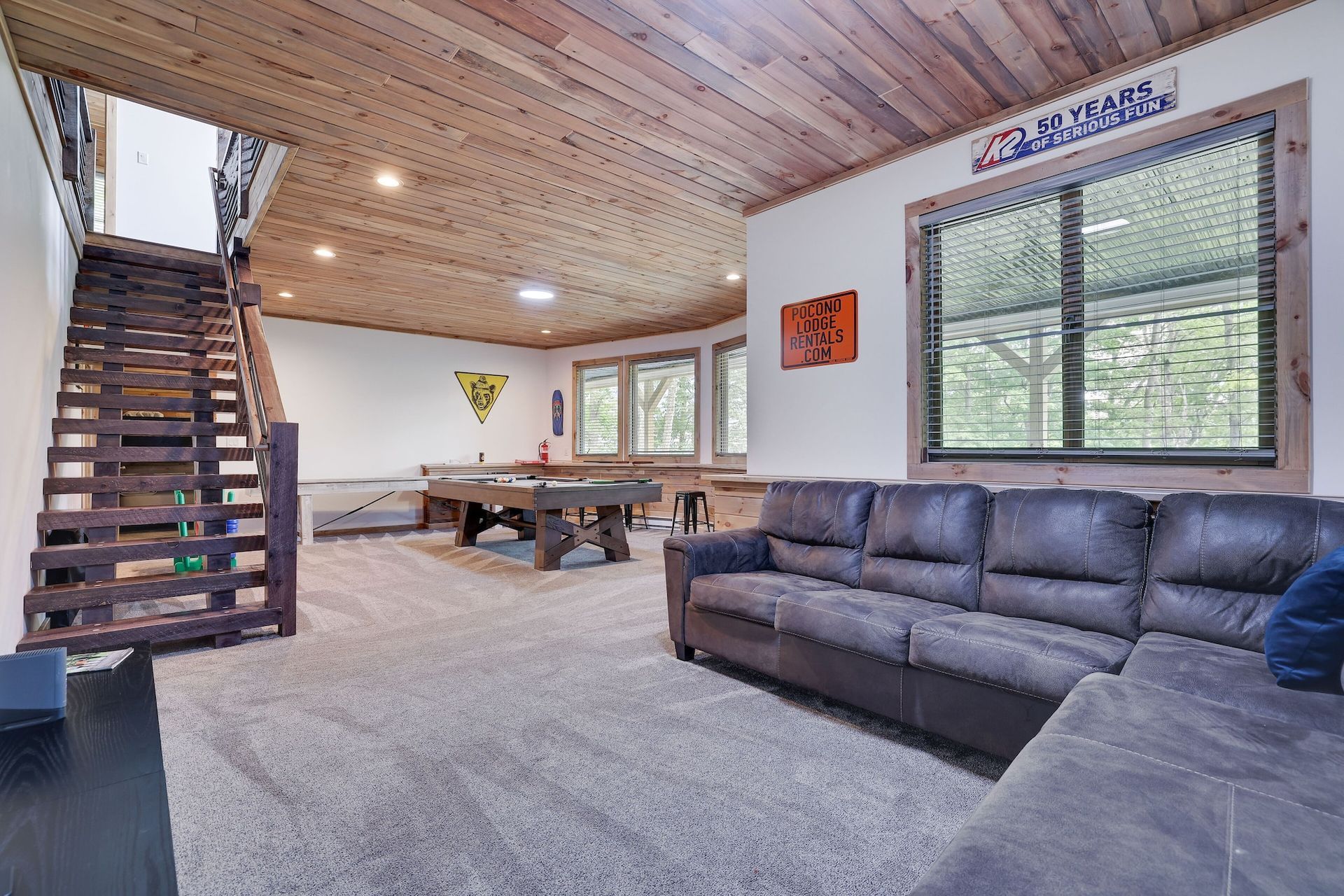 A living room with a couch , pool table and stairs.