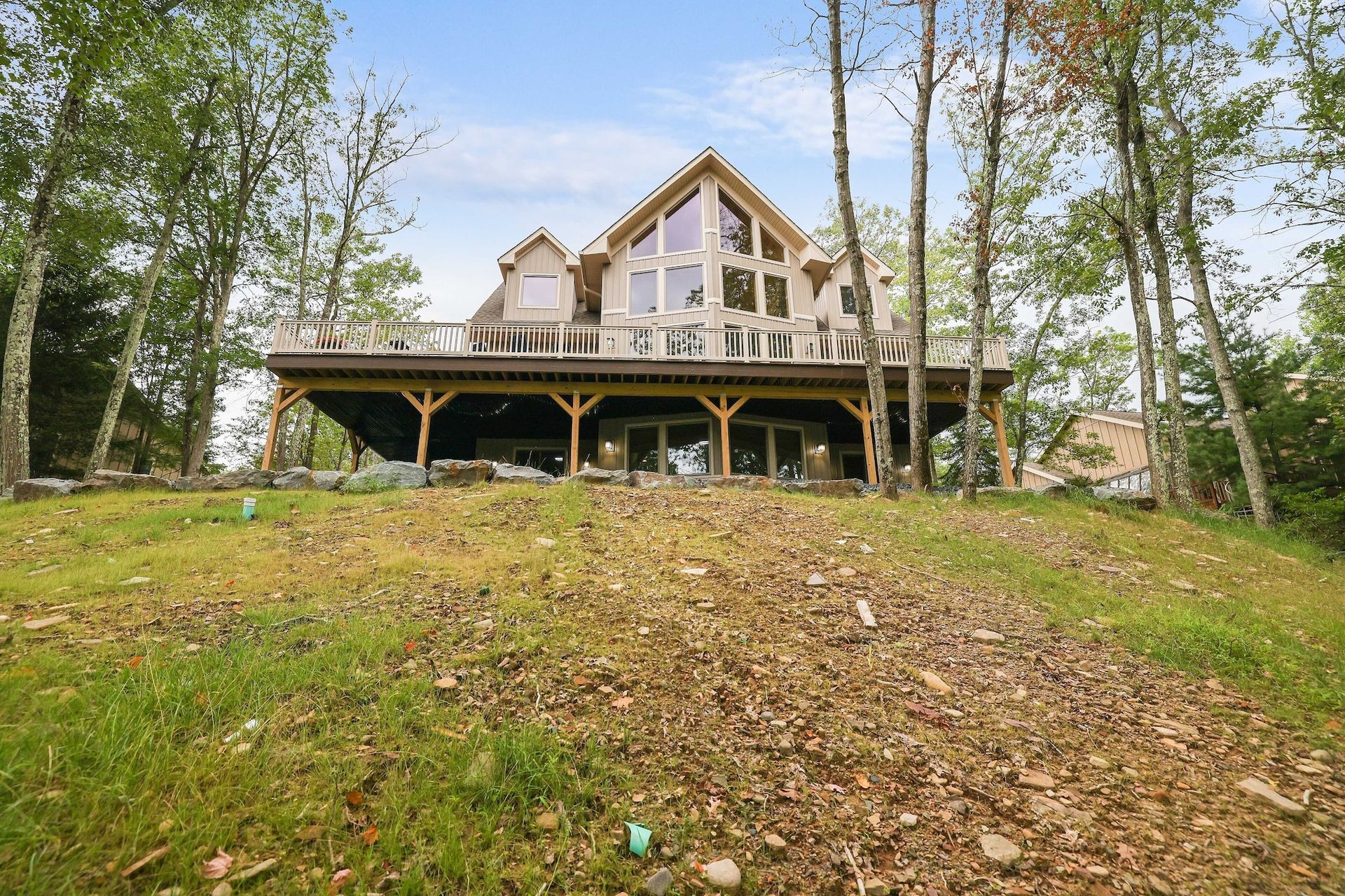 A large house is sitting on top of a grassy hill surrounded by trees.