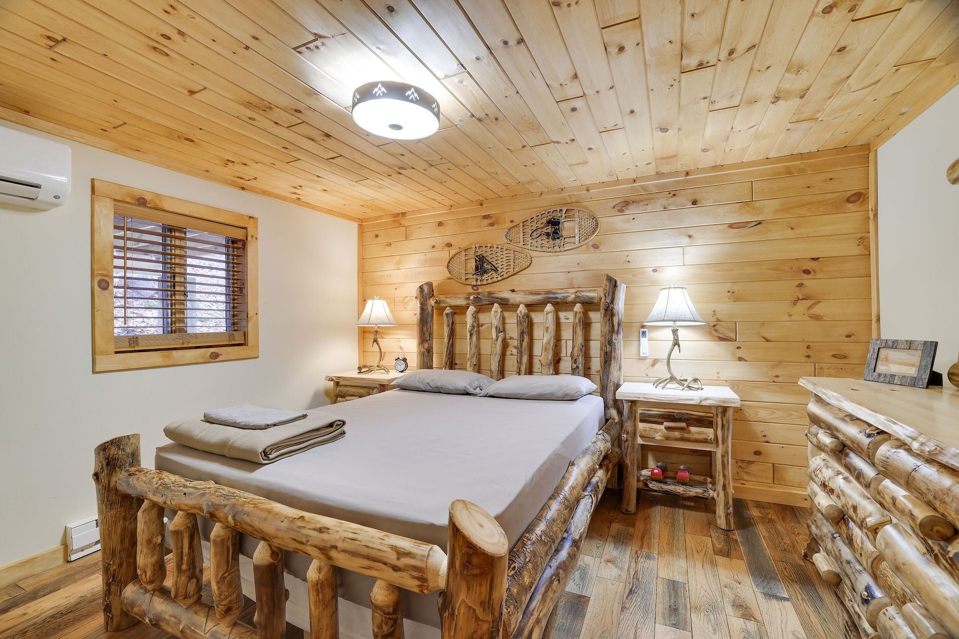 A bedroom in a log cabin with a king size bed and a dresser.