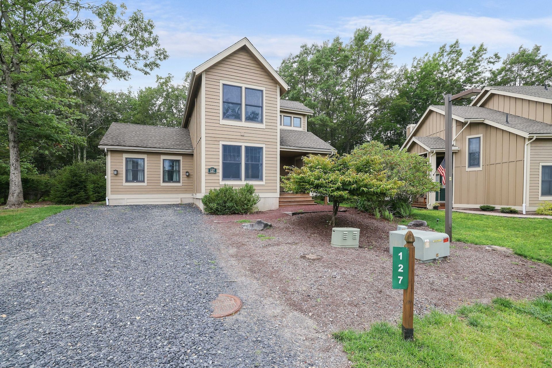 A house with a gravel driveway and a mailbox in front of it.