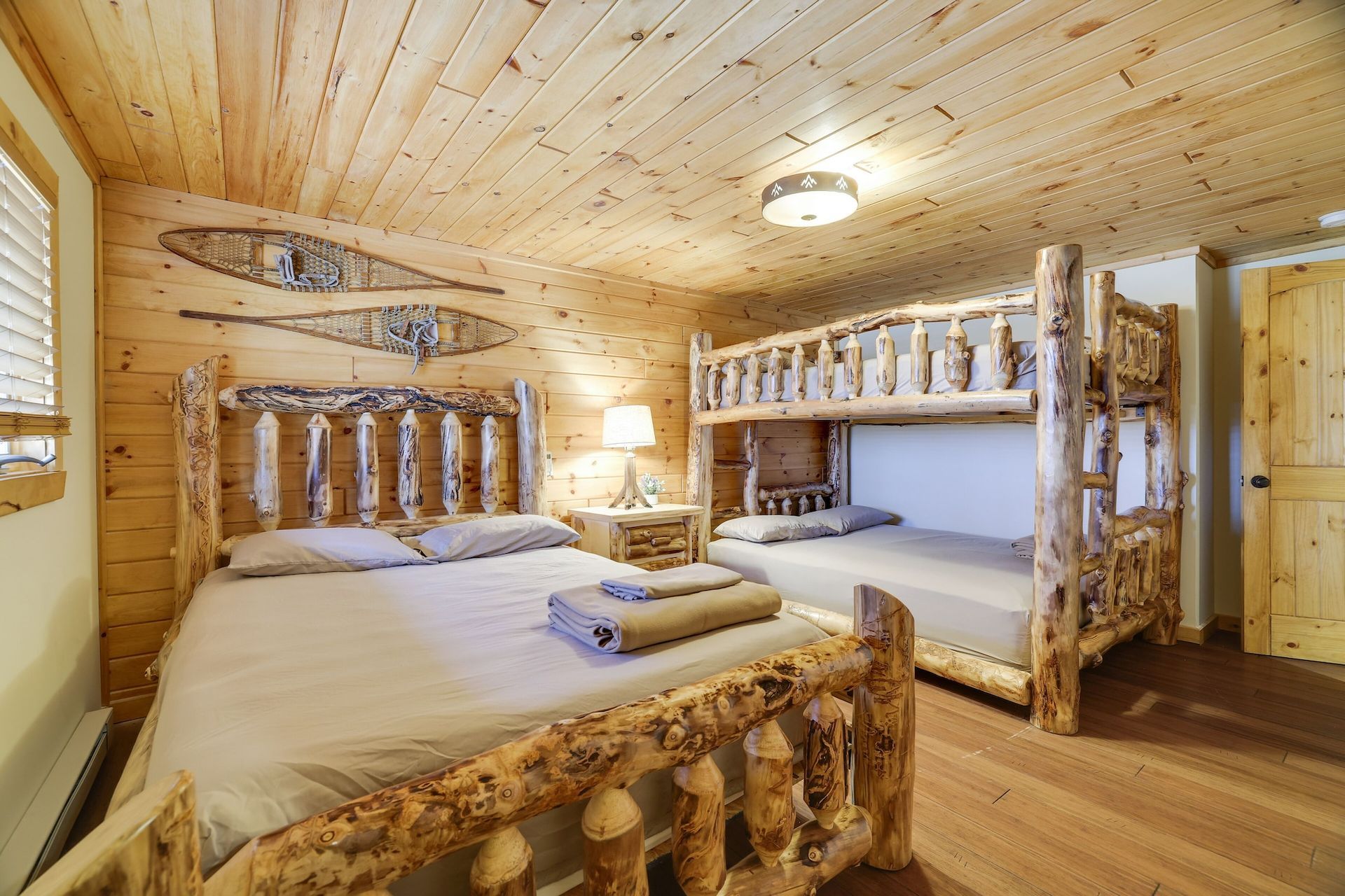 A bedroom in a log cabin with two beds and a bunk bed.