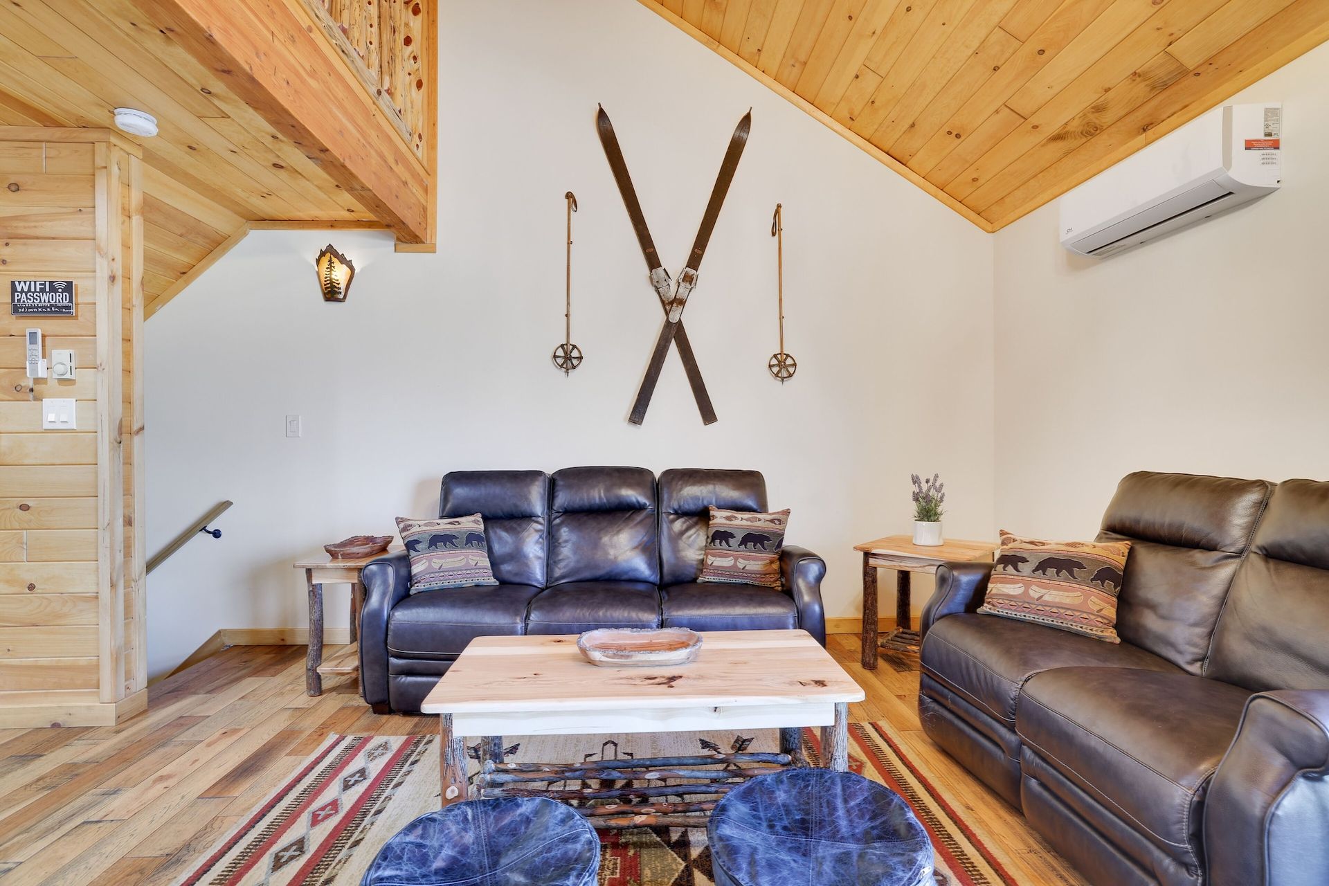 A living room with a couch , coffee table , and skis on the wall.