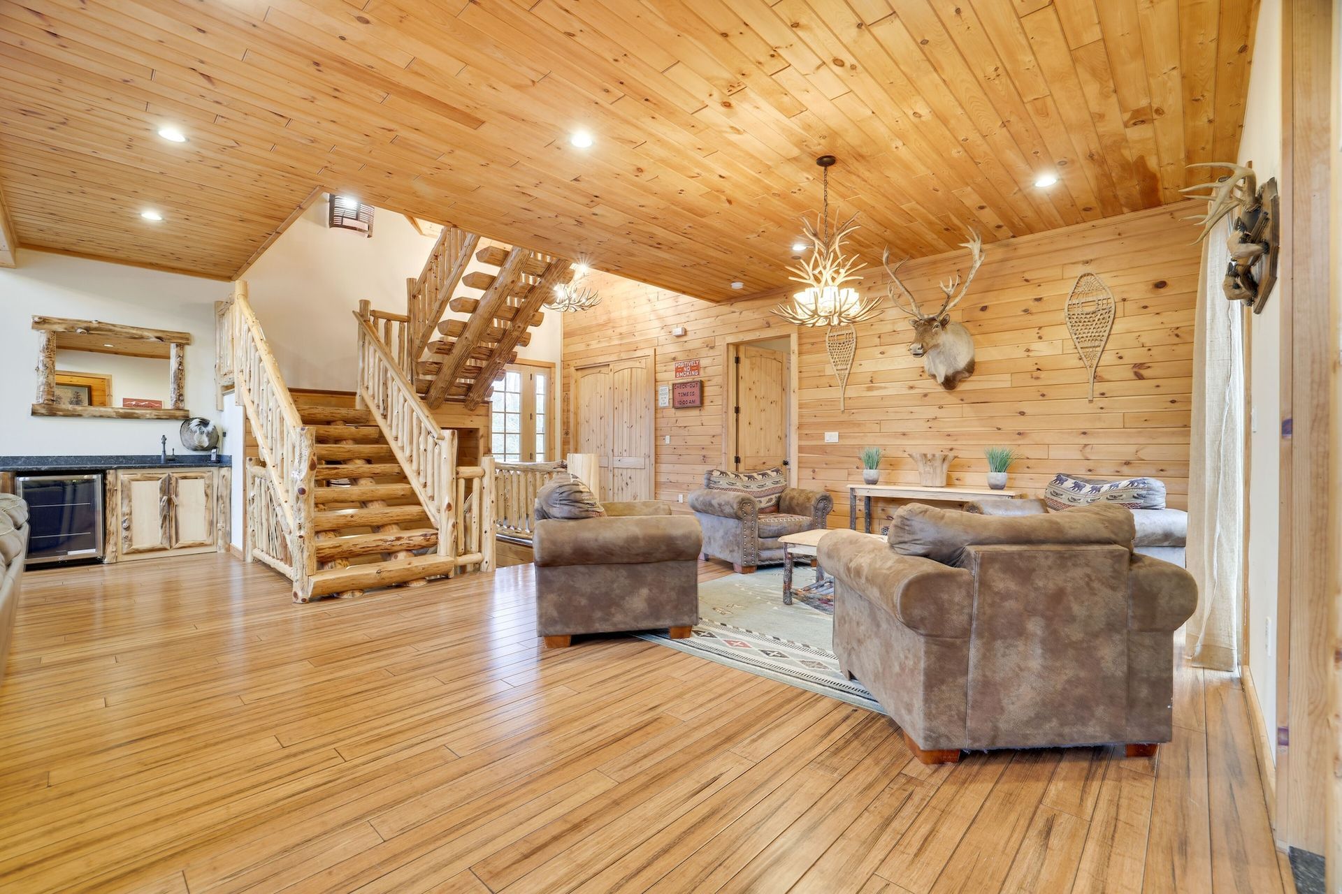 A living room with wooden floors and stairs in a log cabin.