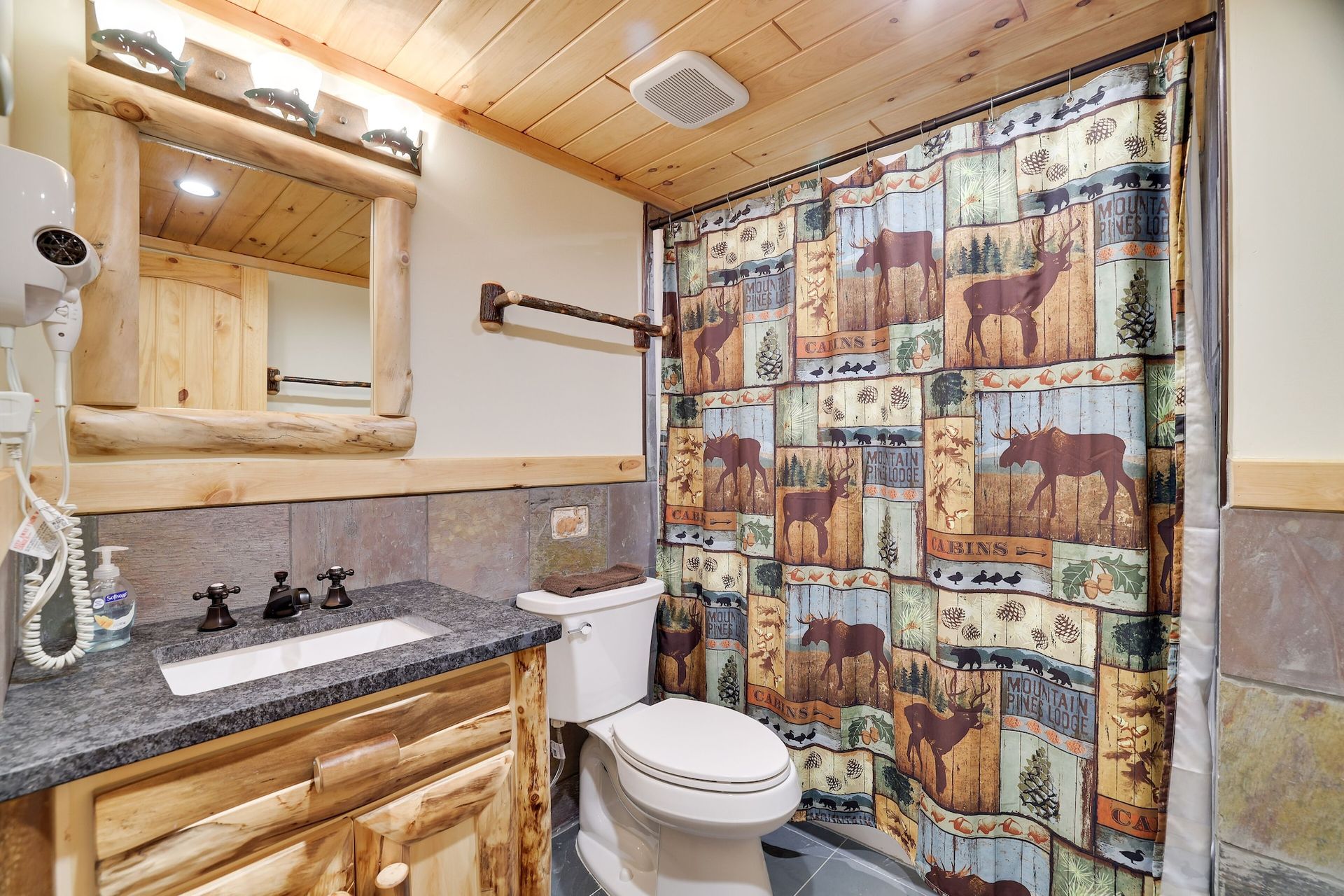A bathroom with a toilet , sink , mirror and shower curtain.