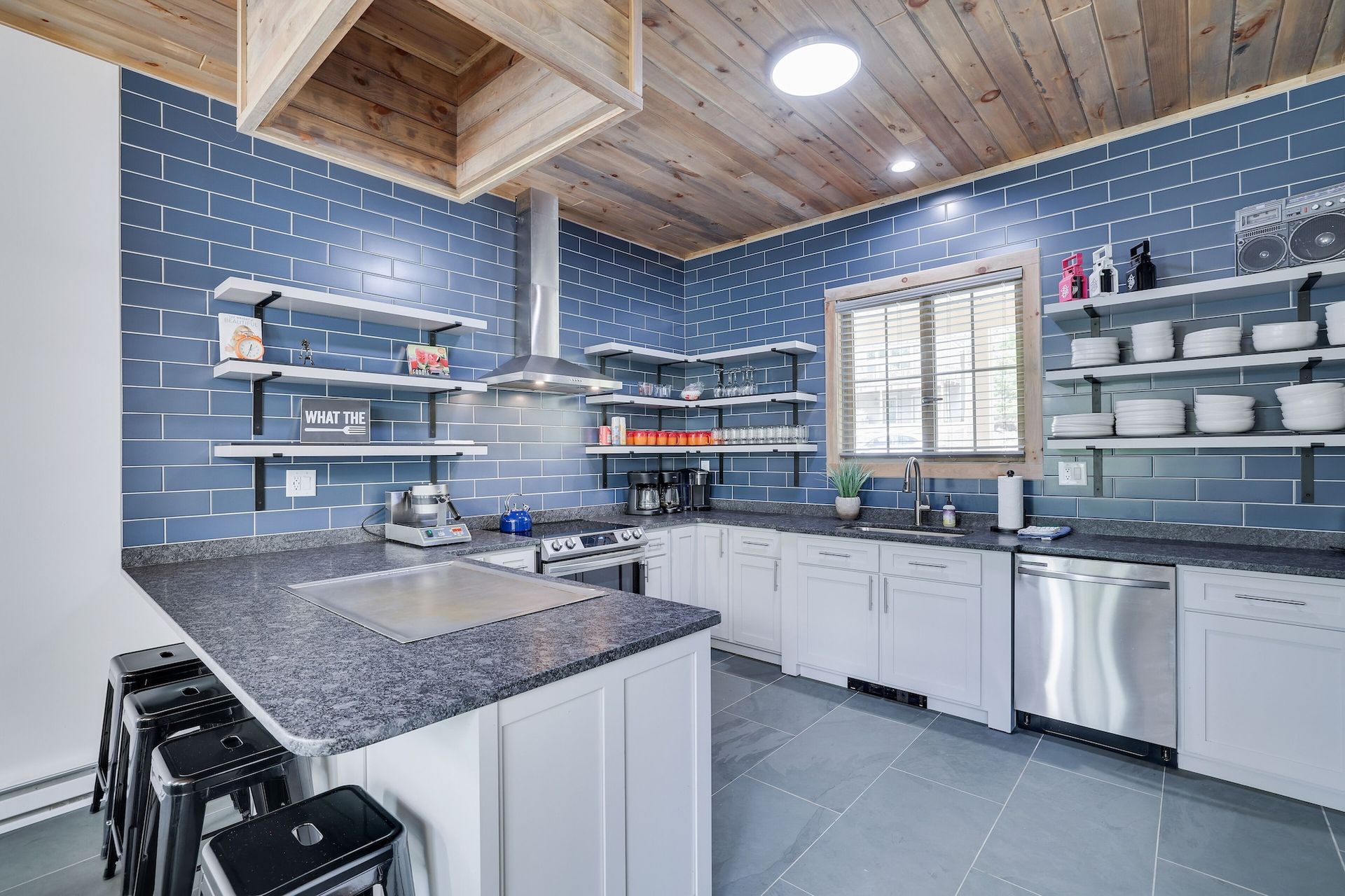 A kitchen with blue brick walls , white cabinets , stainless steel appliances , and granite counter tops.