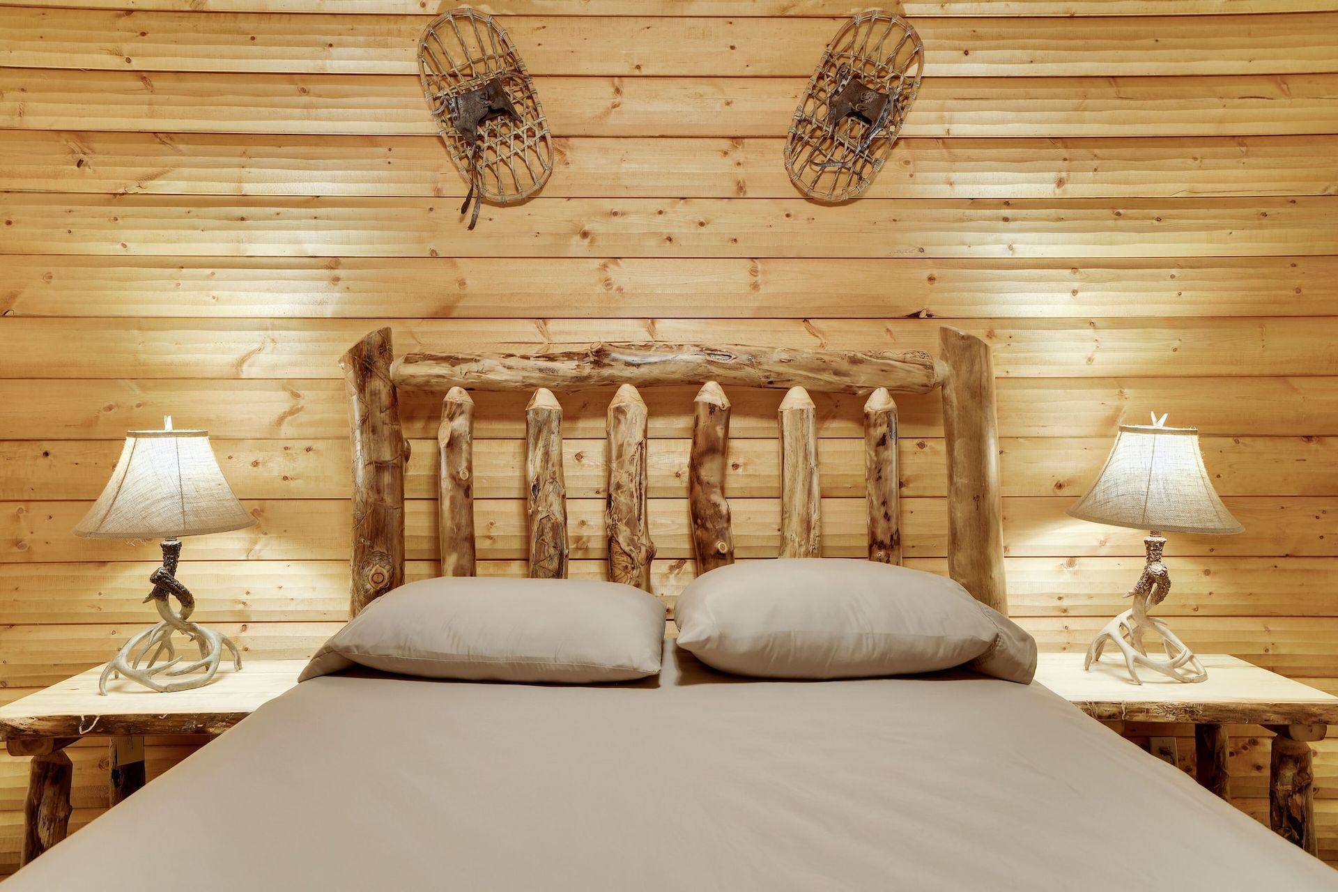 A bedroom in a log cabin with a bed and two lamps.